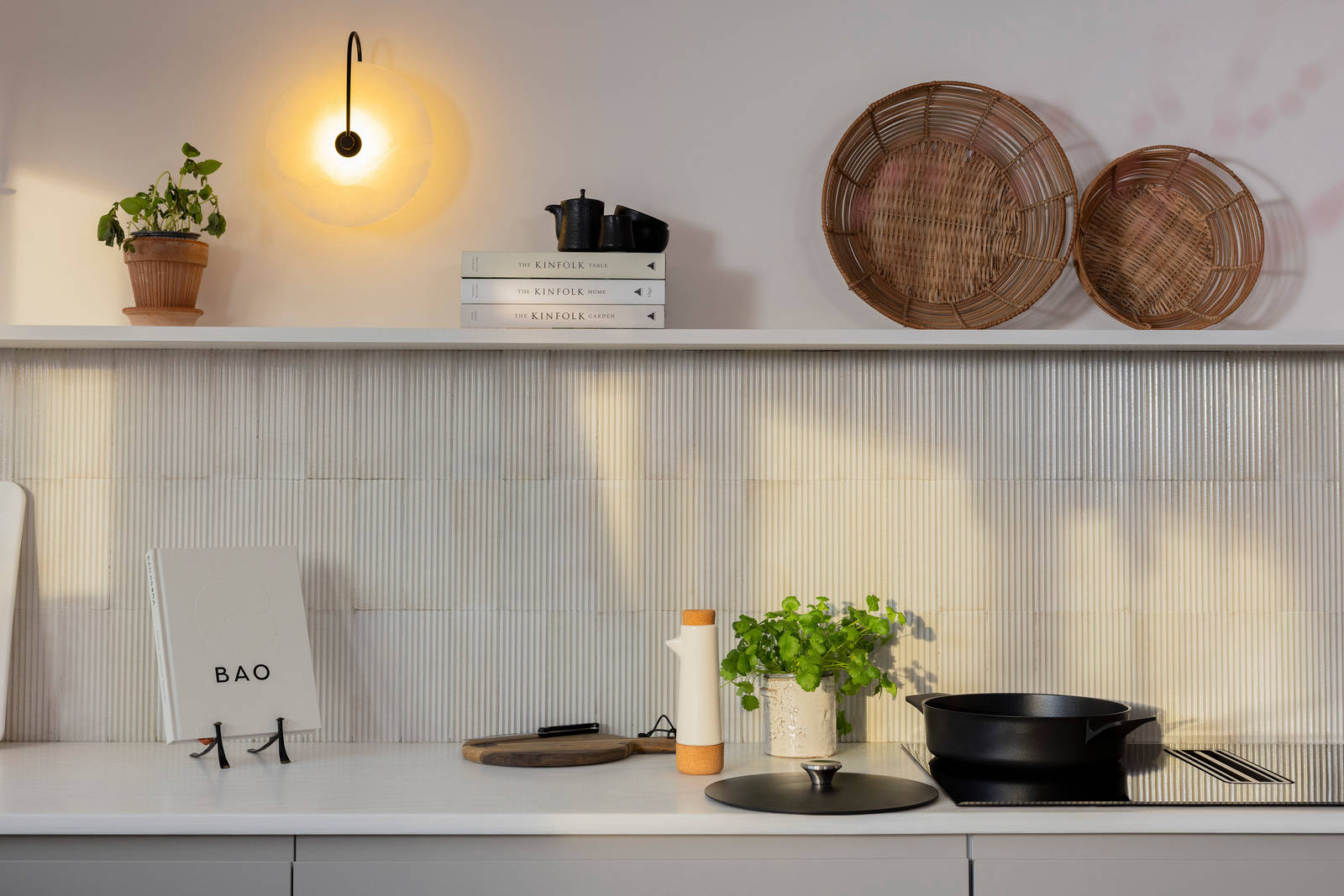 Countertop of Yasmin Wyatts matt finish Luna kitchen from Magnet, splashback and wall shelf, a black skillet pan on the AEG built-in FlexiBridge Hob with Extractor