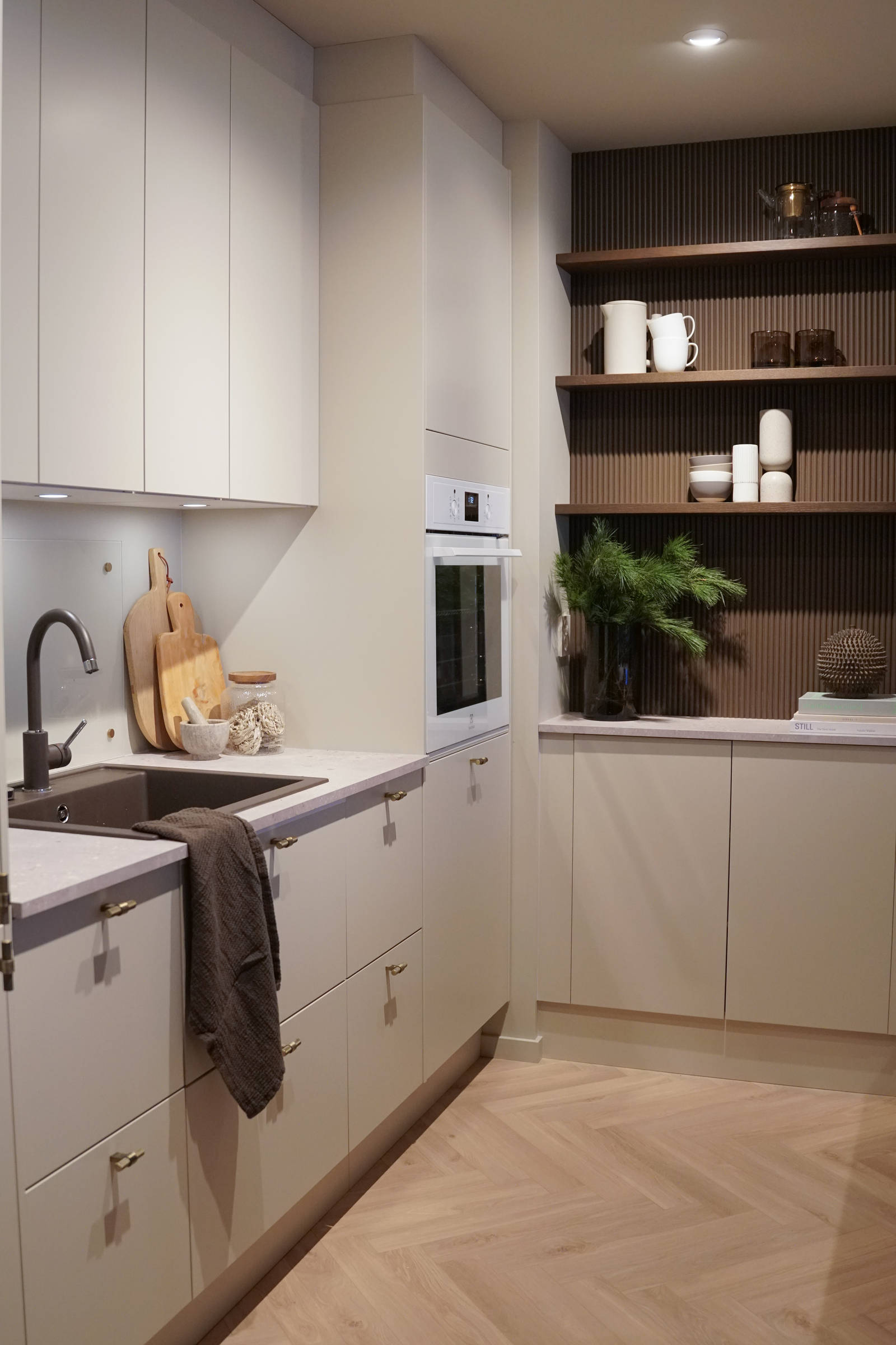 Beige kjøkken med rifled tre veggpanel , sort vask og sort kran