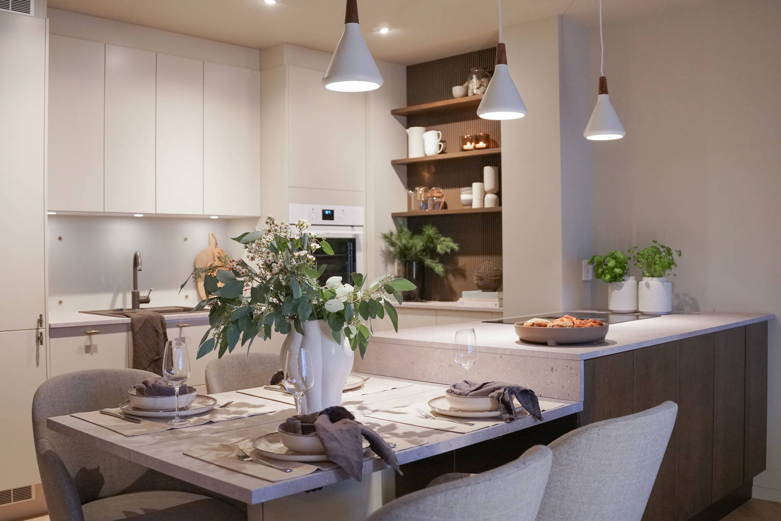 Veggen i kaffenisjen, der hyllene er festet er dekket med rillede dekorplater fra Deco Systems, malt i en egenkomponert farge som ligner beisfargen på kjøkkenøya