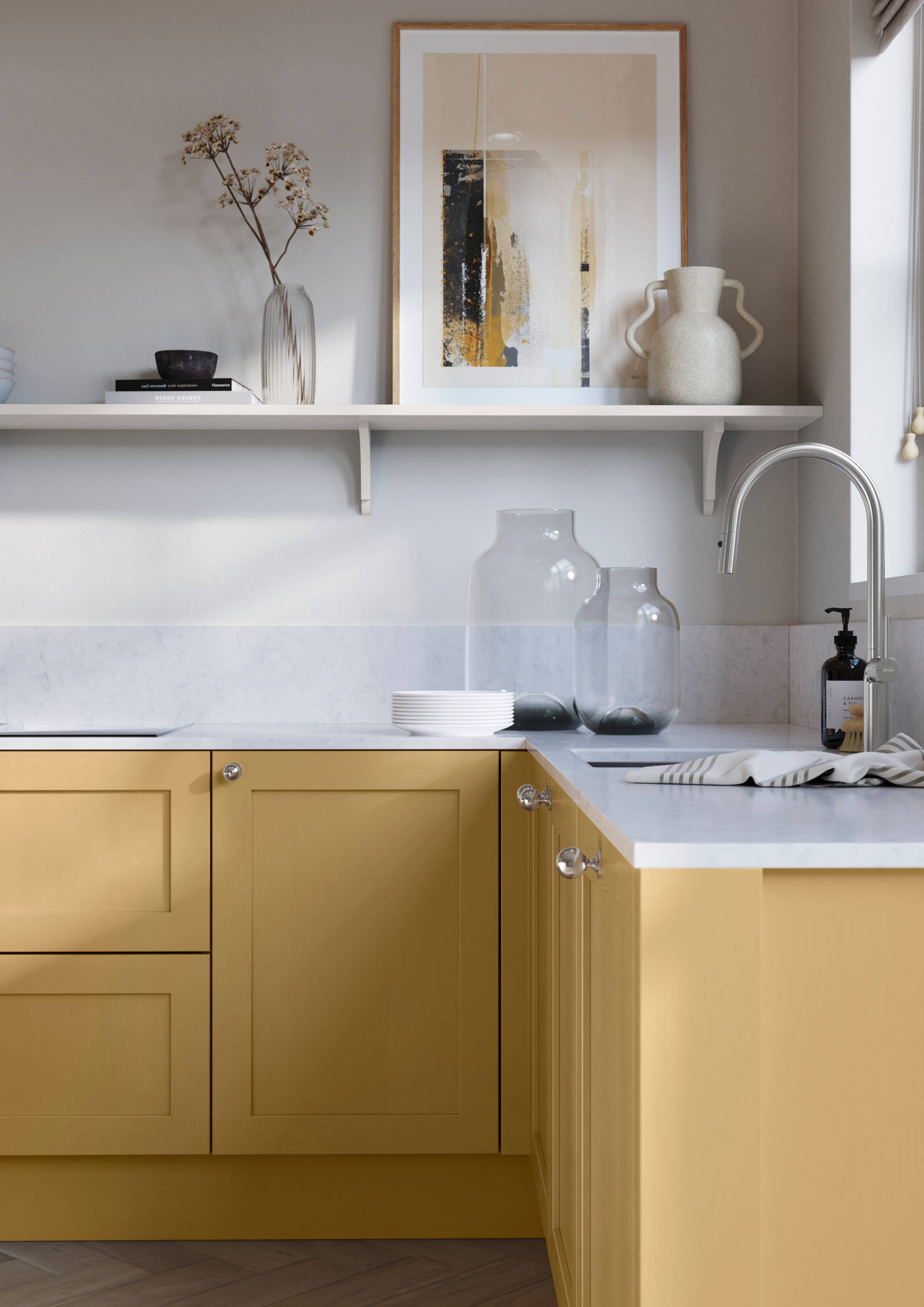 Wardley Harvest kitchen cabinetry with steel knobs, steel tap, white marbled worktop and matching backsplash. An open shelf on the wall above cabinets with ceramics and a vase of flowers.