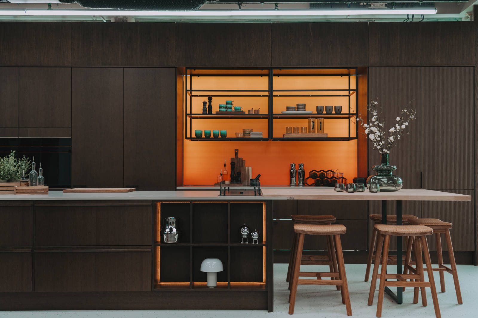 Kjøkken i modell Favn fra Sigdal i lekker eikefinér, som er beiset i fargen Nøtt, kjøkkenøya med barkrakker og åpne hyller i sort metallramme i God Morgen Norge studion sin