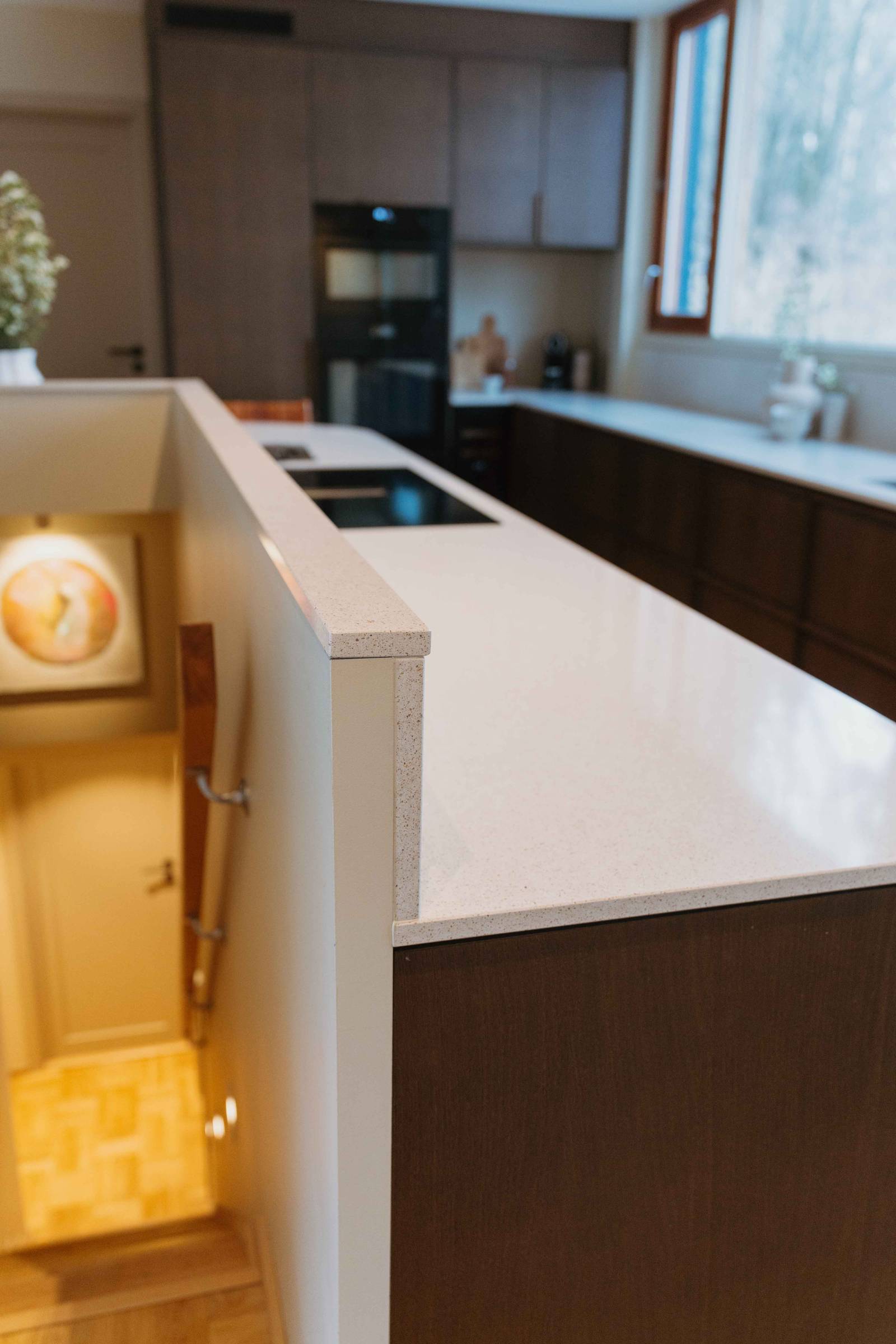 Vy över köksö i Liv och Hallvards Signatur Ekbacken-kök från Marbodal, med brunbetsad fanerad eklucka, matchande handtag i trä och bänkskiva i kvartskomposit