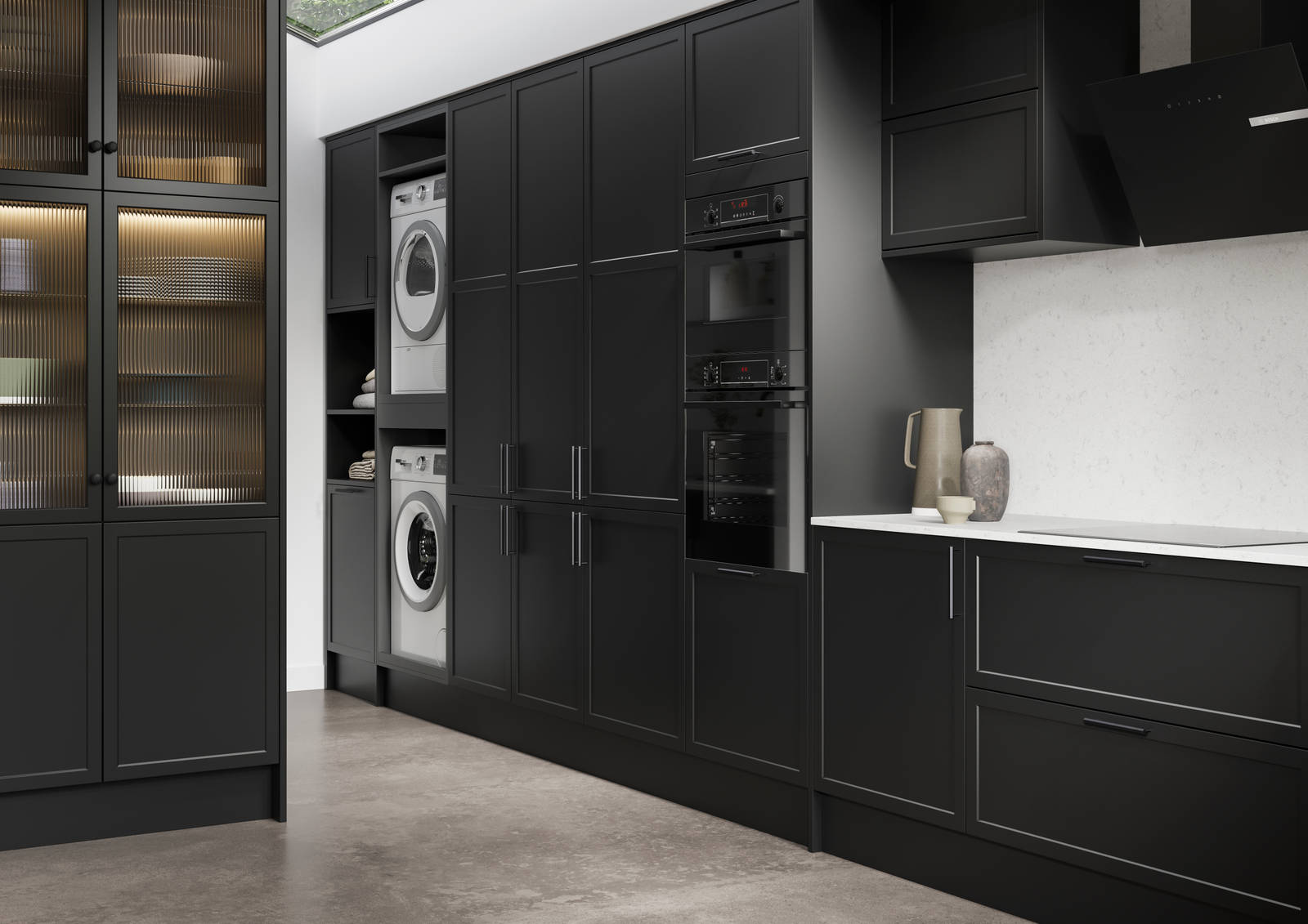 View of Modern Shaker Brunswick Sumi Black laundry room from kitchen, with integrated laundry machine and dryer as well as ovens in tall cabinetry, white worktop and splashback Silestone Miami Vena and vitrine cabinets with fluted glass doors.