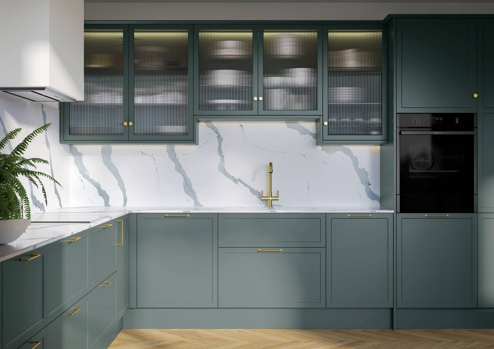 Modern Shaker kitchen Brunswick Spruce, a muted green shade, wall cabinets with fluted glass doors, Quartz Bianco Calacatta worktop and splashback, brass accessories like knobs, handles and tap, and a light wood herringbone floor.