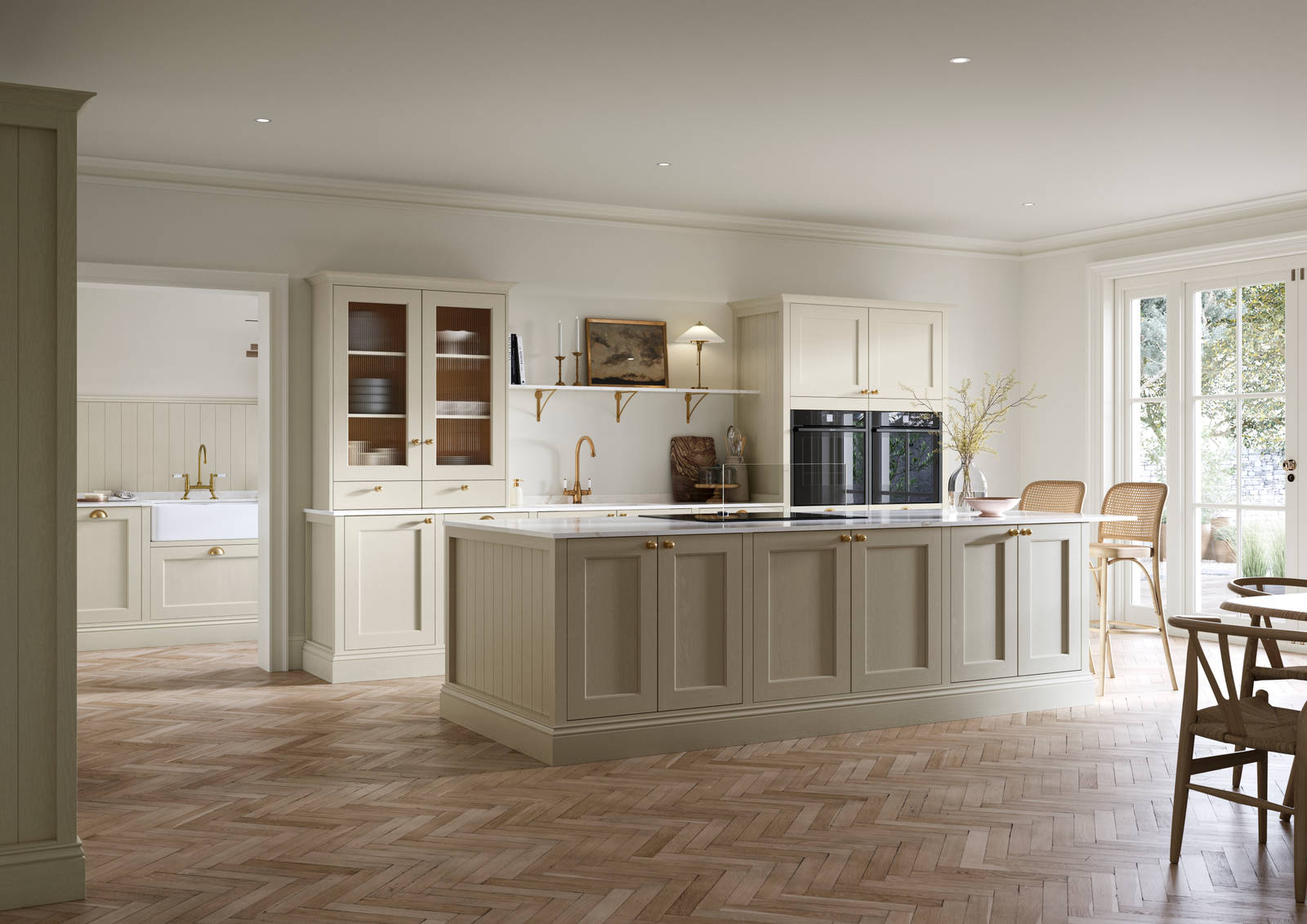 Open plan living room and Traditional Shaker-style kitchen Ludlow Parchment with tactile woodgrain, flute glass vitrine cabinets,  brass acessories like handles and tap, integrated ovens, a kitchen island and light wood herringbone flooring.