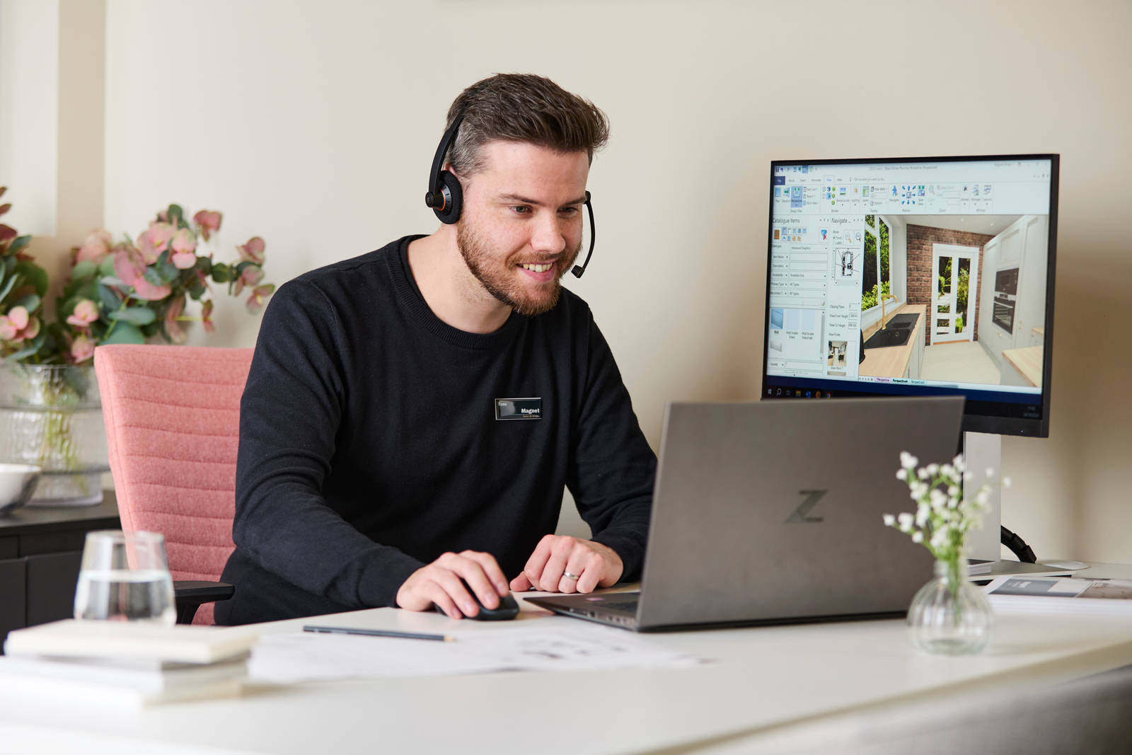 Magnet colleague at a desk, wearing a headset designing a kitchen on a computer
