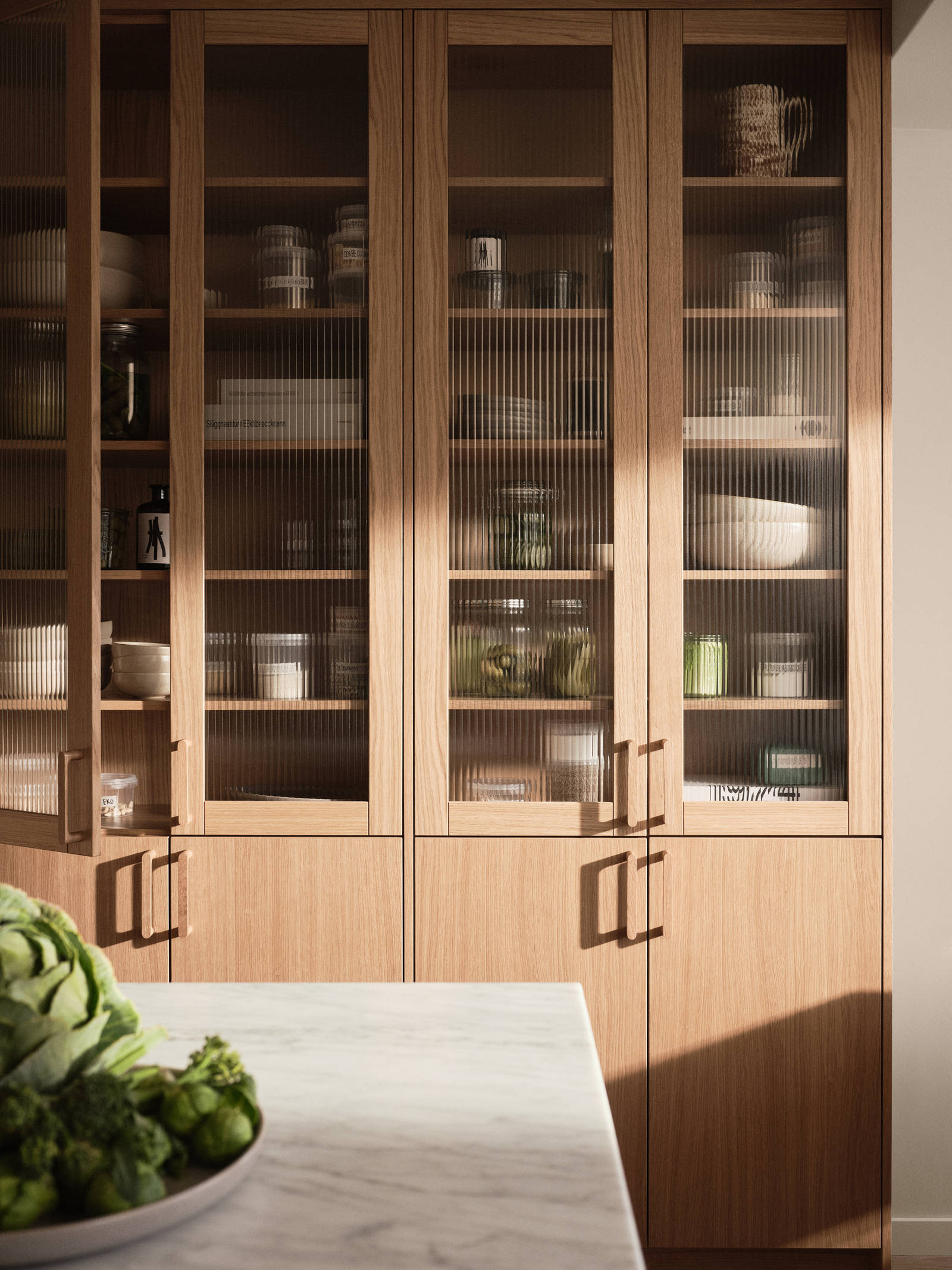 Siri Barjes kök Ekbacken från Marbodal, högskåp med ekluckor och vitrinluckor med ram i ek, matchande handtag i trä, köksö.