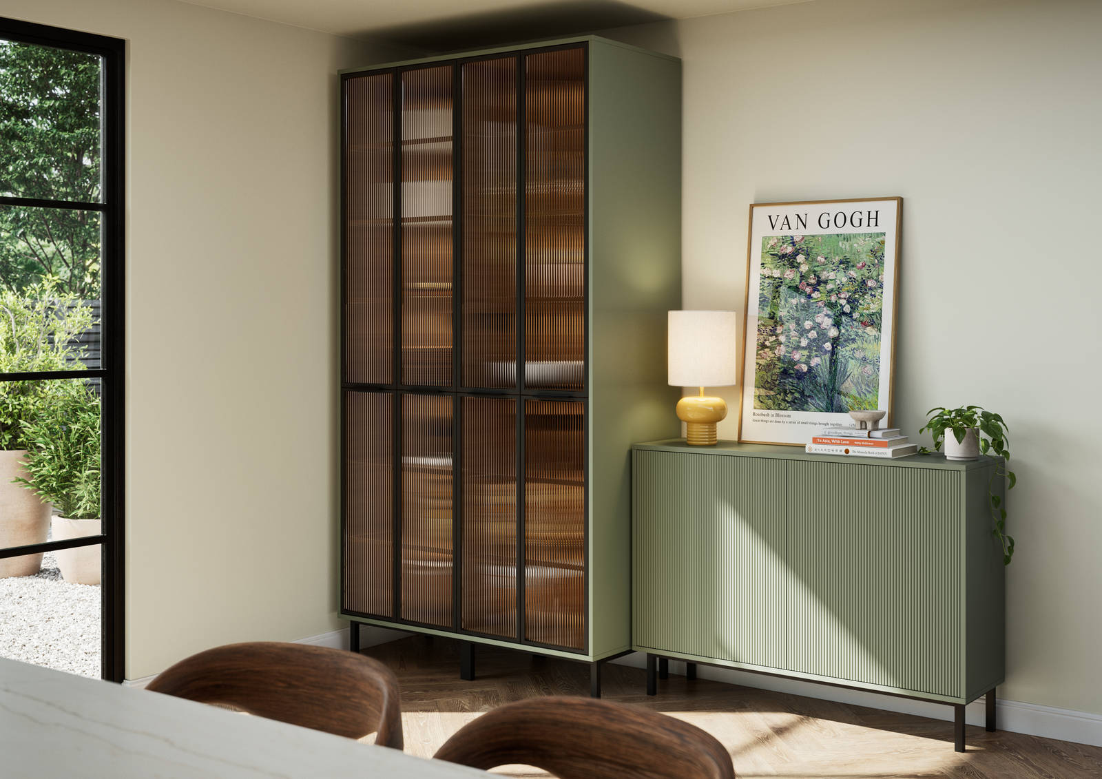 Vitrine with fluted glass in black metal frames, on green cabinet next to green fluted kitchen fronts on sideboard cabinets on black metal legs.