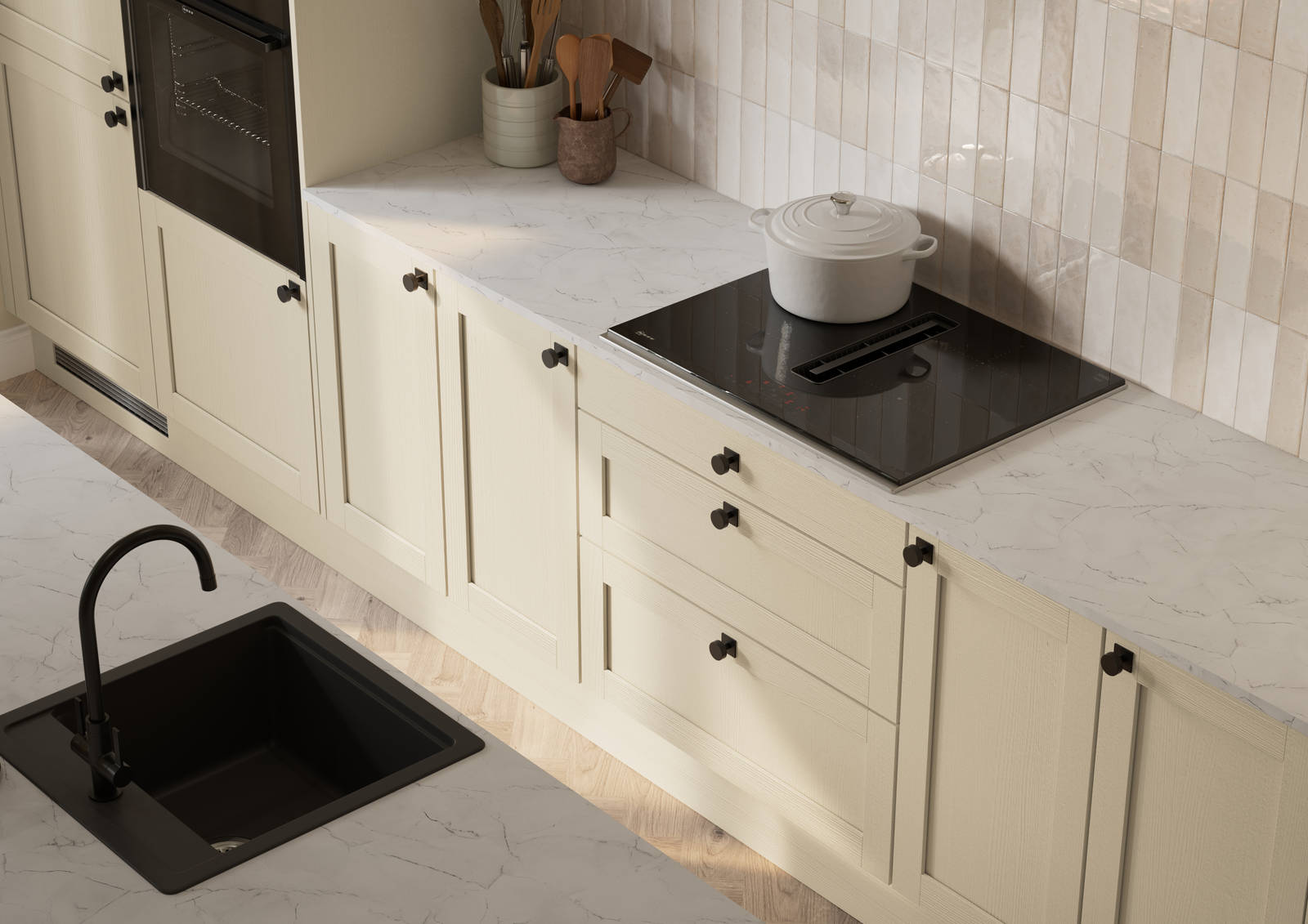 View from above of contemporary Shaker kitchen Ambleside from Magnet in neutral shade Sand with black sink and tap in kitchen island, induction hob with extractor, marbled worktop and black knobs.
