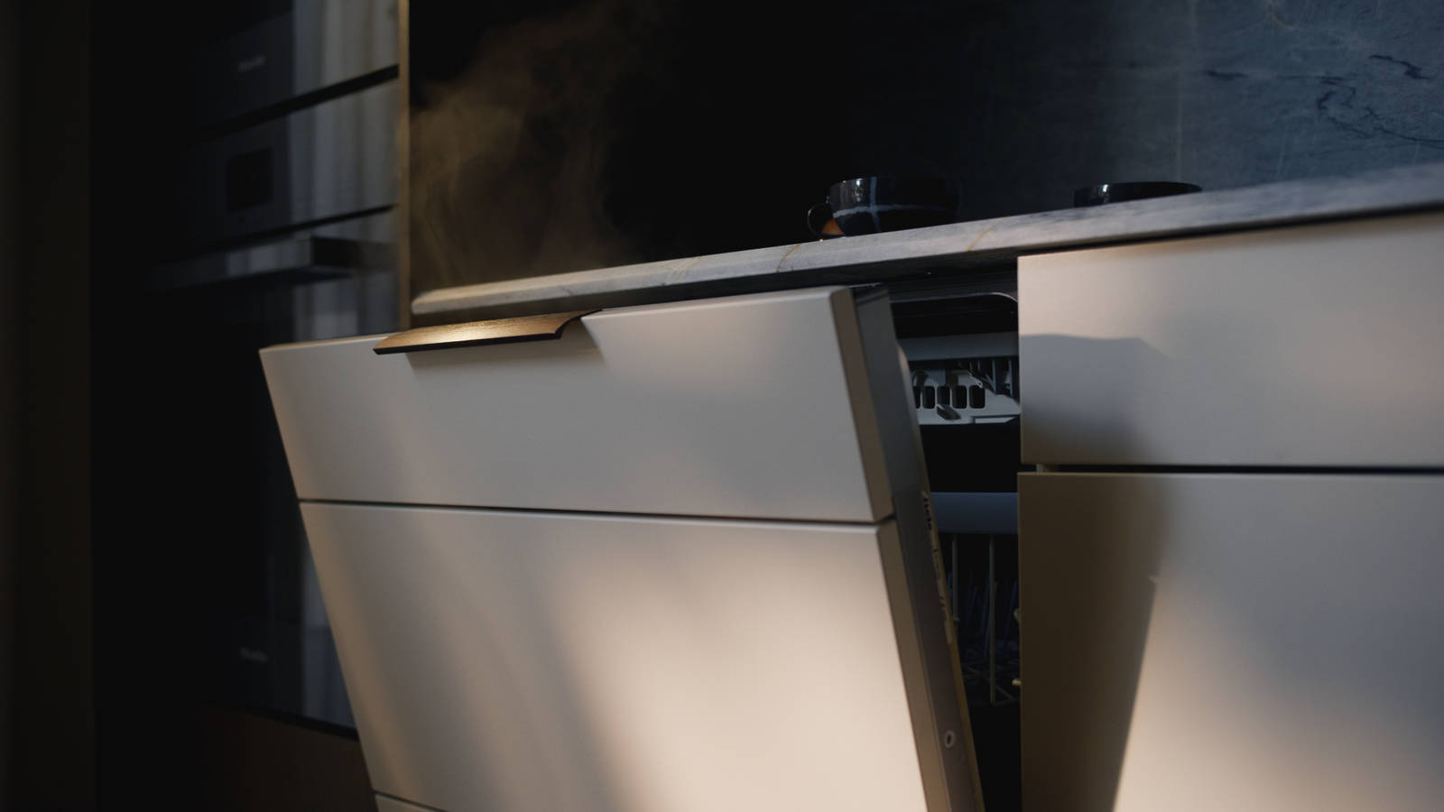Ånga som stiger över ett kök ur en diskmaskin som står på glänt.