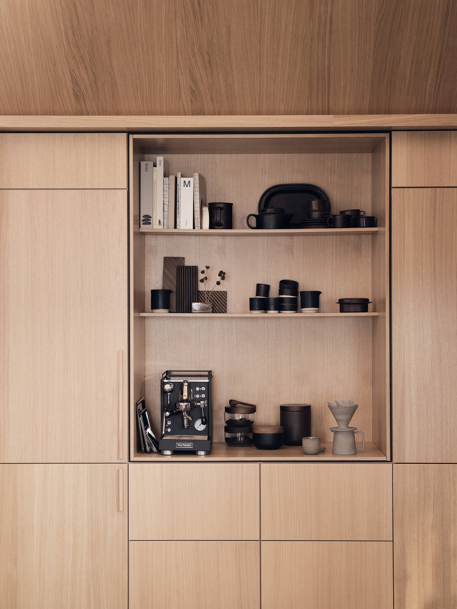 Köket Ekbacken natur från Marbodal i ekfanér med vertikal träådring, högskåp och ett öppet skåp med plats för kaffemaskin, inramad med en skuggning vilket skapar en arkitektonisk premiumkänsla.