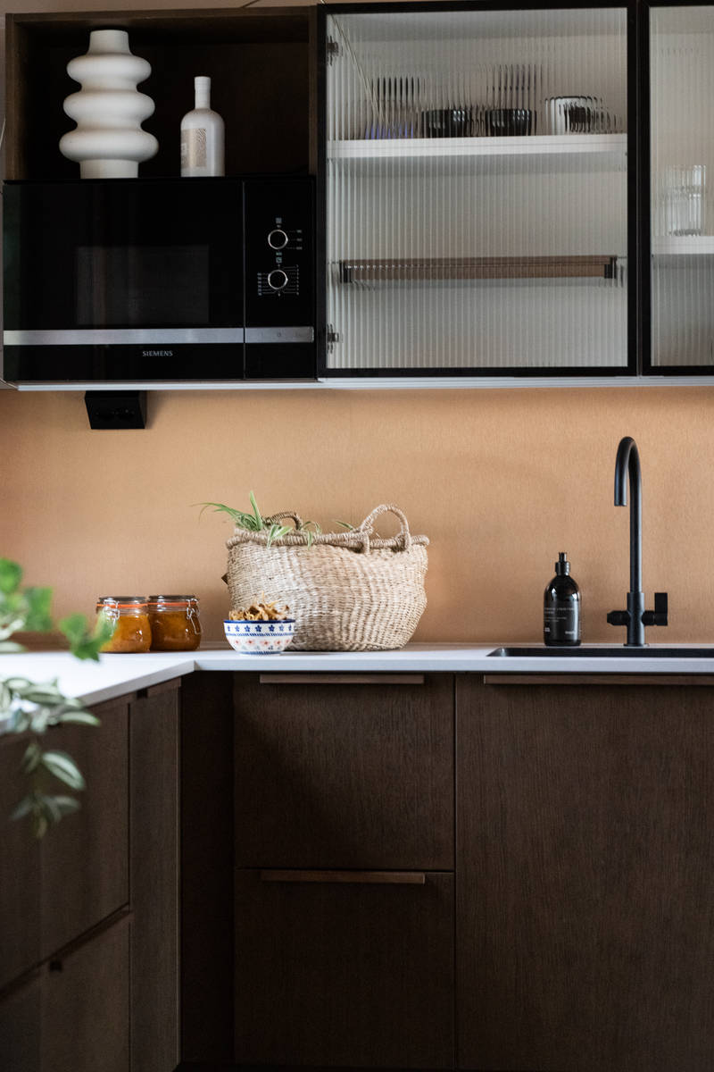 Nordic Nature tammiviilukeittiö, jossa vaalea laminaattitaso, musta hana sopii vitriiniseinäkaappien mustaan ​​metallirunkoon uritettu lasiovilla