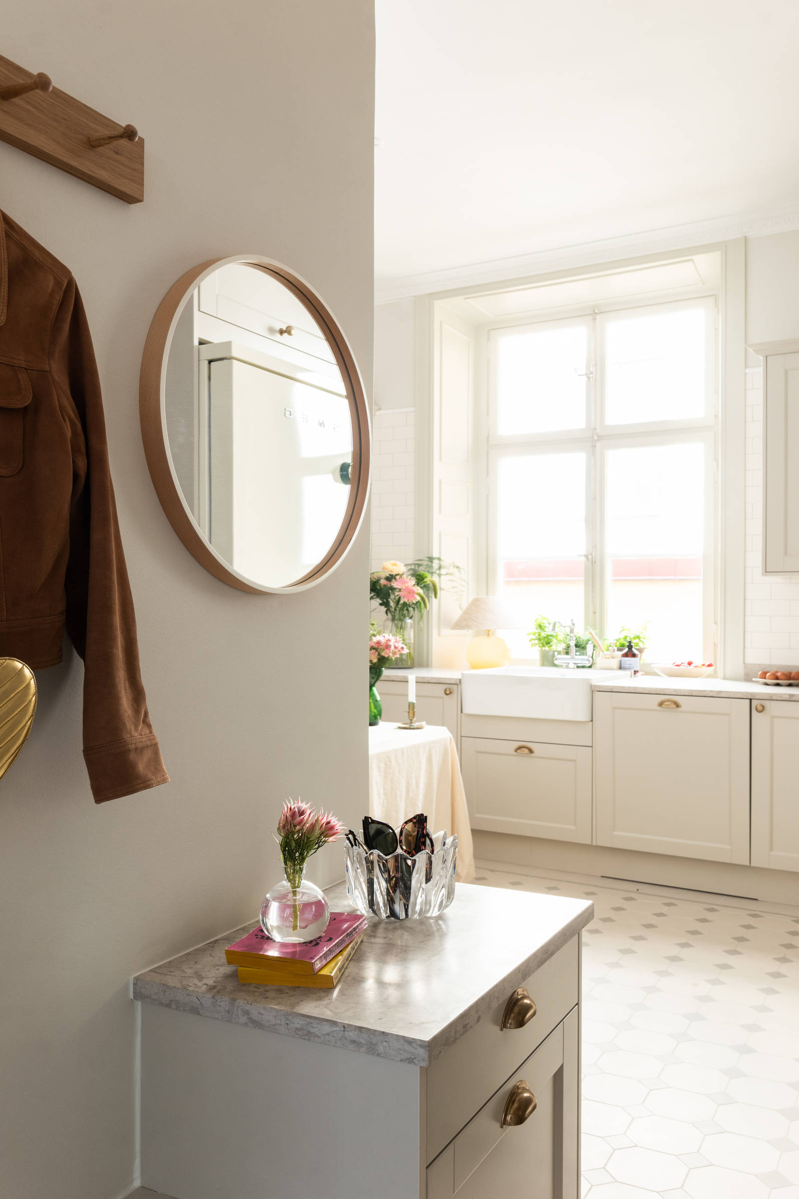 Hallskåp i Sandra Beijers lägenhet, lantliga luckan Fagerö i beige kulören Sand, låga skåp med knoppbräda och en spegel ovanför.