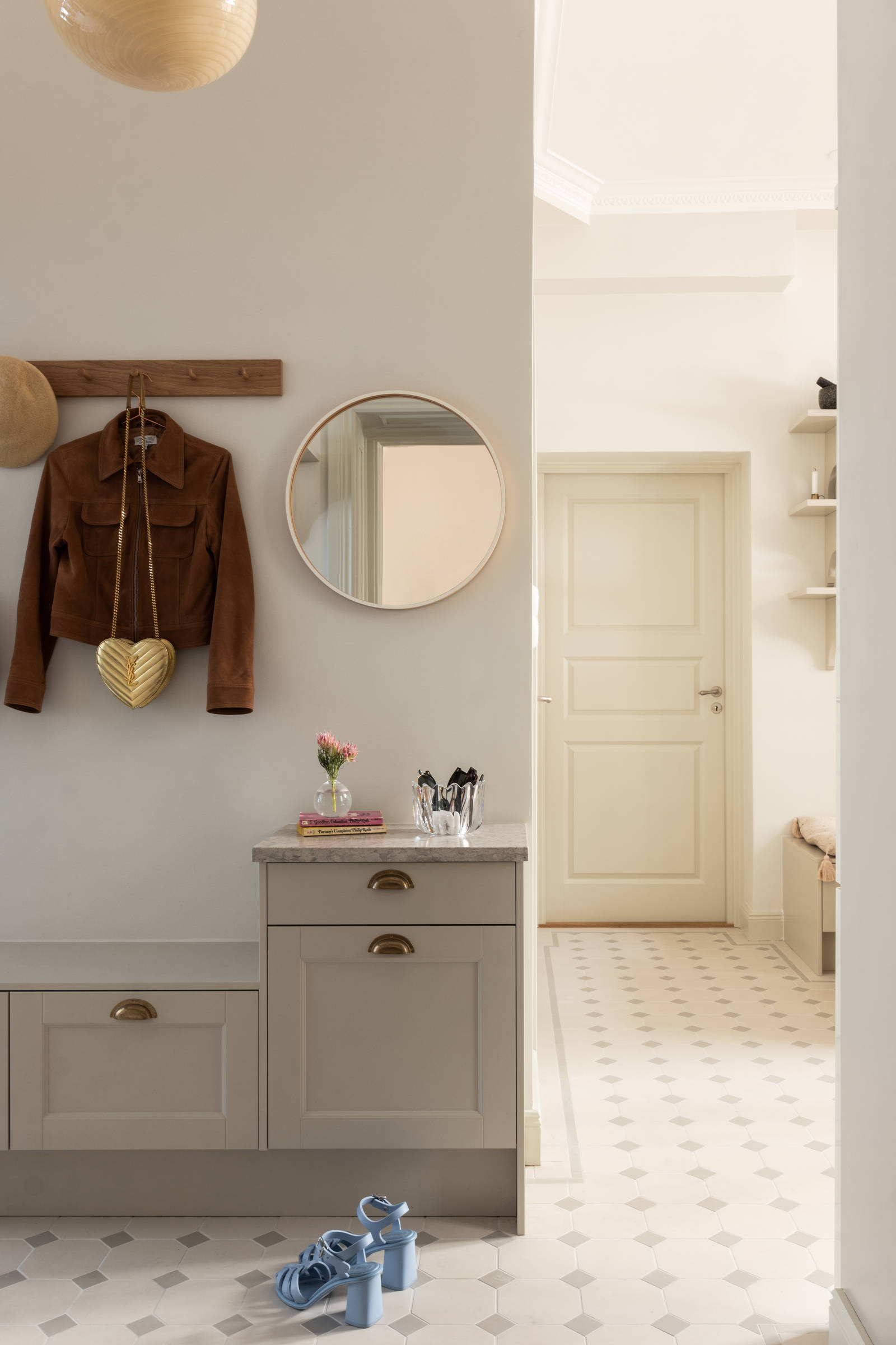 Hallskåp i Sandra Beijers lägenhet, lantliga luckan Fagerö i beige kulören Sand, låga skåp med knoppbräda och en spegel ovanför.