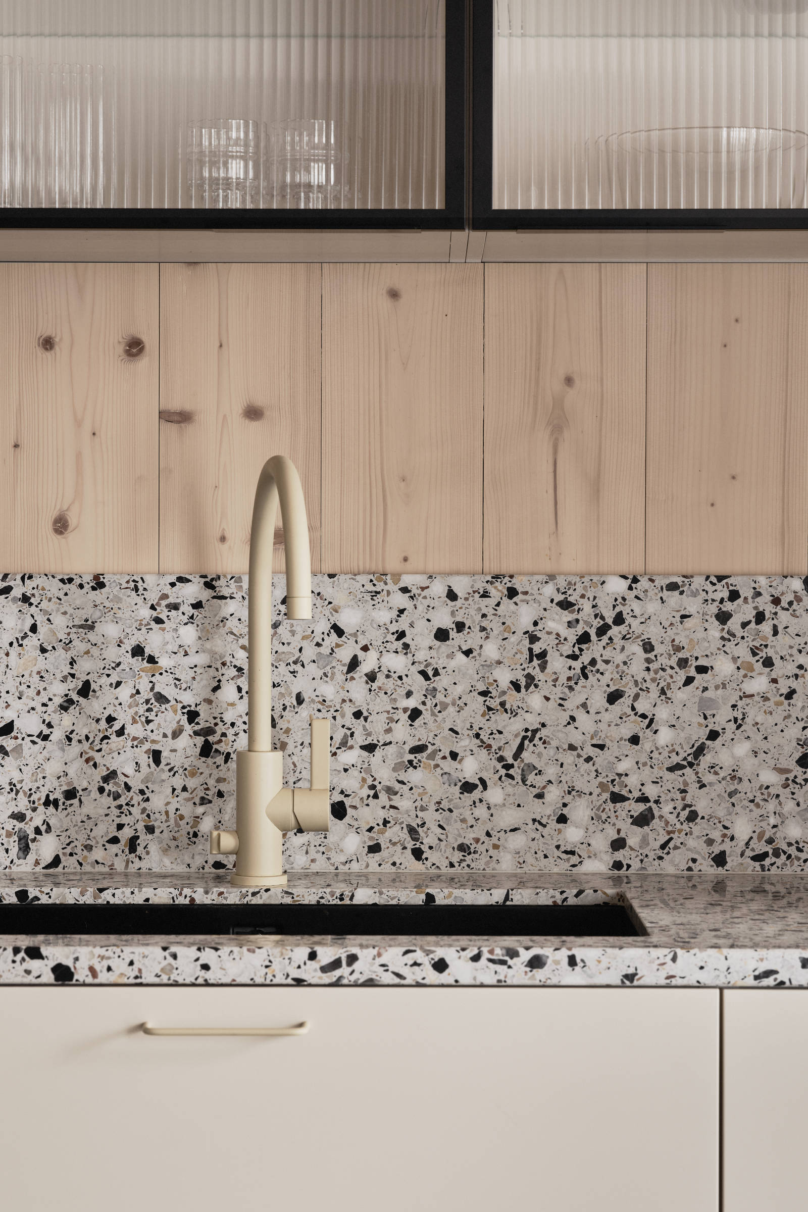 Beige blandare och svart diskho i terrazzo-bänkskiva med matchande stänkskydd i Edd Ruchtons Grand design kök i beige Arkitekt Plus-kök från Marbodal