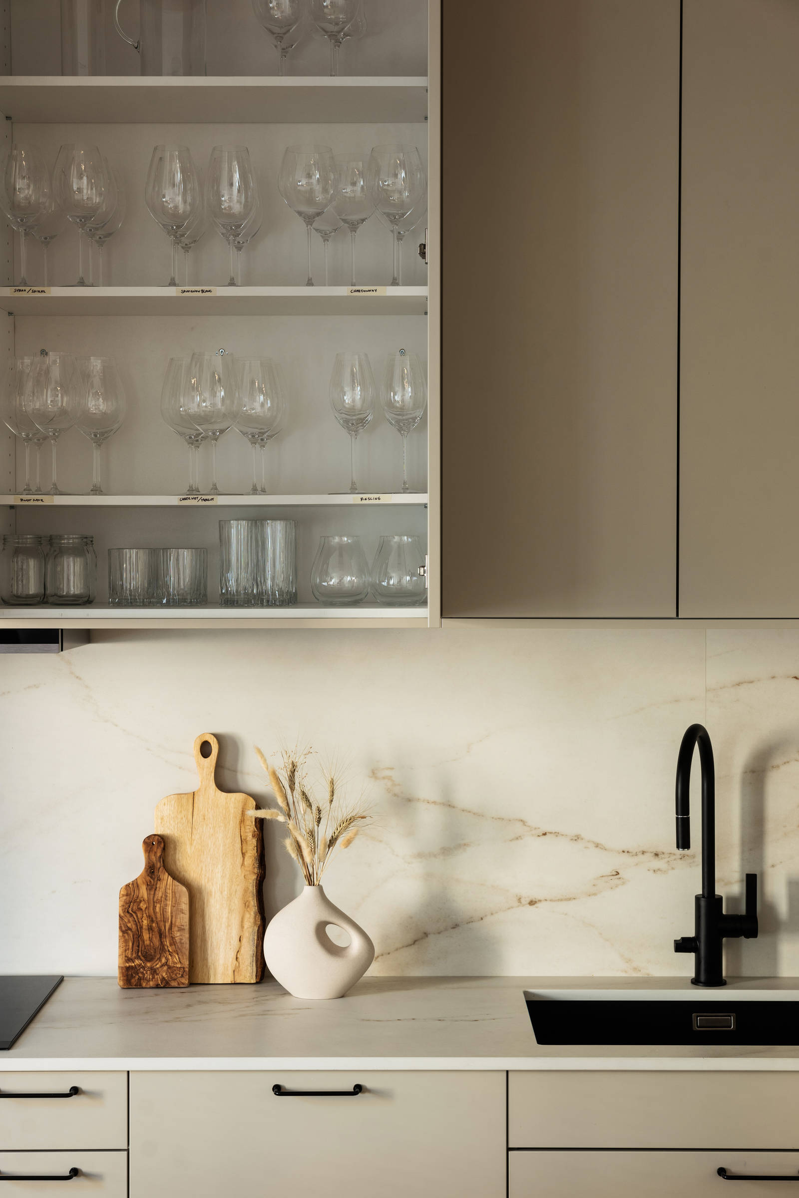 Matt svart blandare och diskho i Filip Poons kök från Marbodal, Arkitekt Plus Sand med svarta handtag och Dekton bänkskiva samt stänkskydd