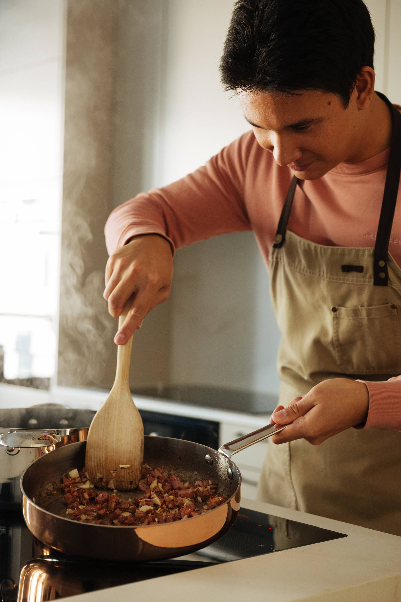 Filip Poon lagar mat i sitt clean och eleganta Arkitekt Plus Sand-kök från Marbodal med Dekton-bänkskiva och matchande stänkskydd