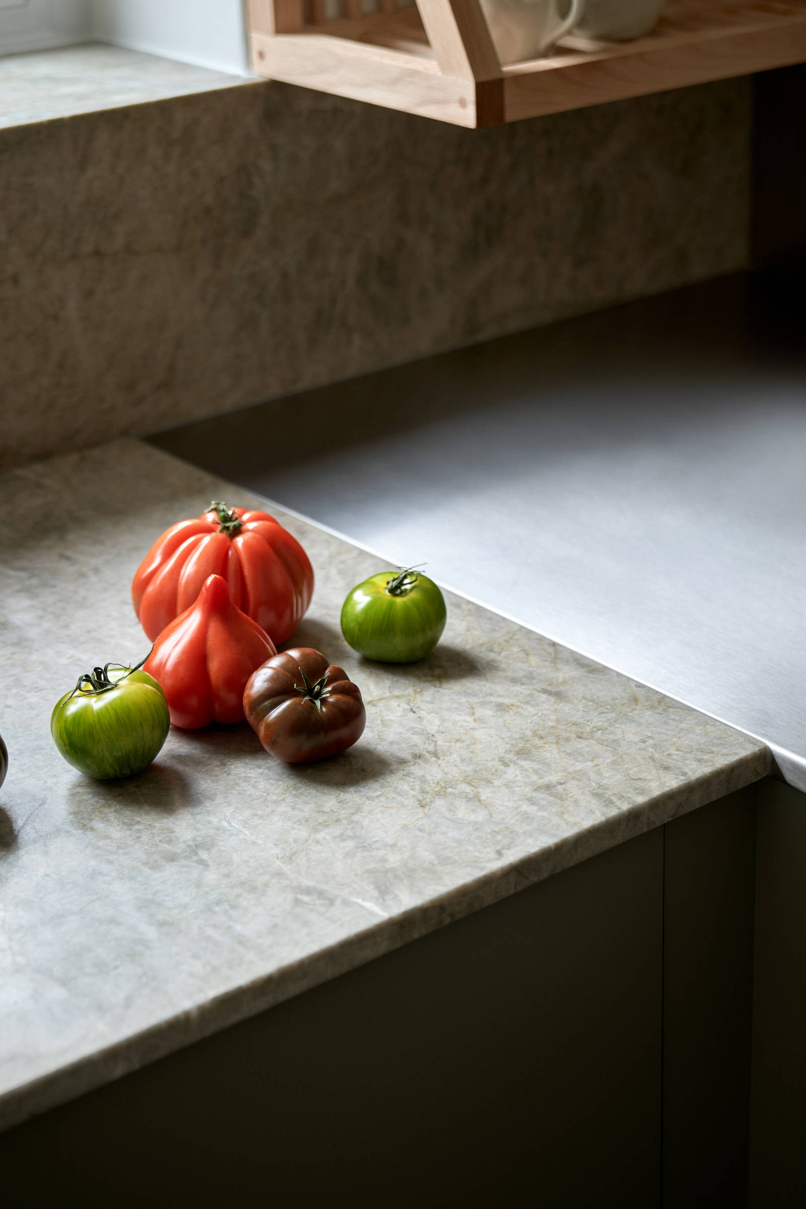 Gröna köket Arkitekt plus i kulören Tall med en vedspis och bänkskiva i kvartsit