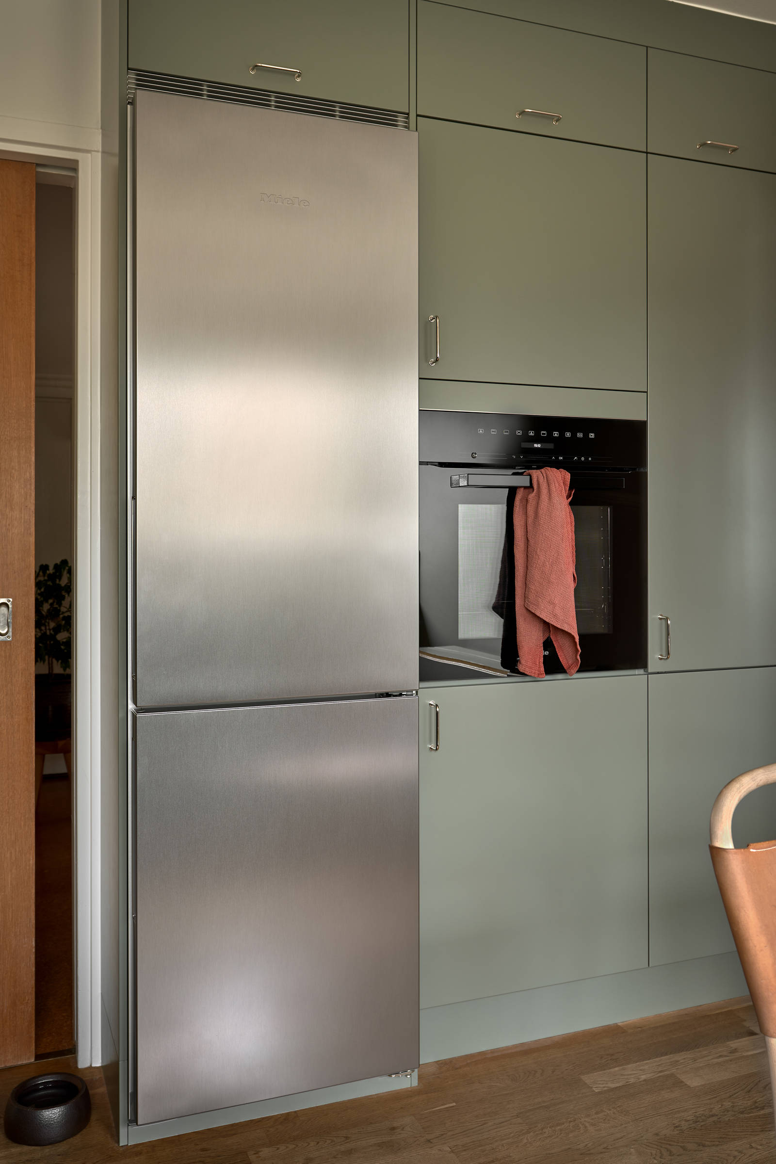 Gröna köket Arkitekt plus i kulören Tall med en vedspis och bänkskiva i kvartsit