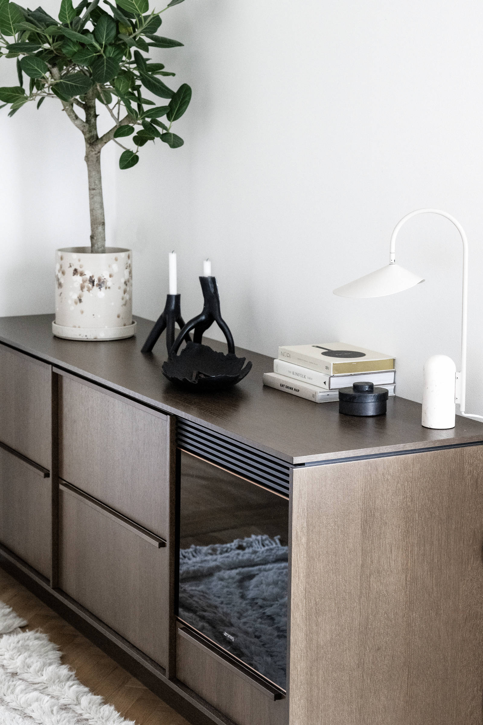 Närbild av bänkskåp med möbelkänsla som sideboard med inbyggd vinkyl, i Signatur Ekbacken brunbetsad ekfanér med matchande handtag.