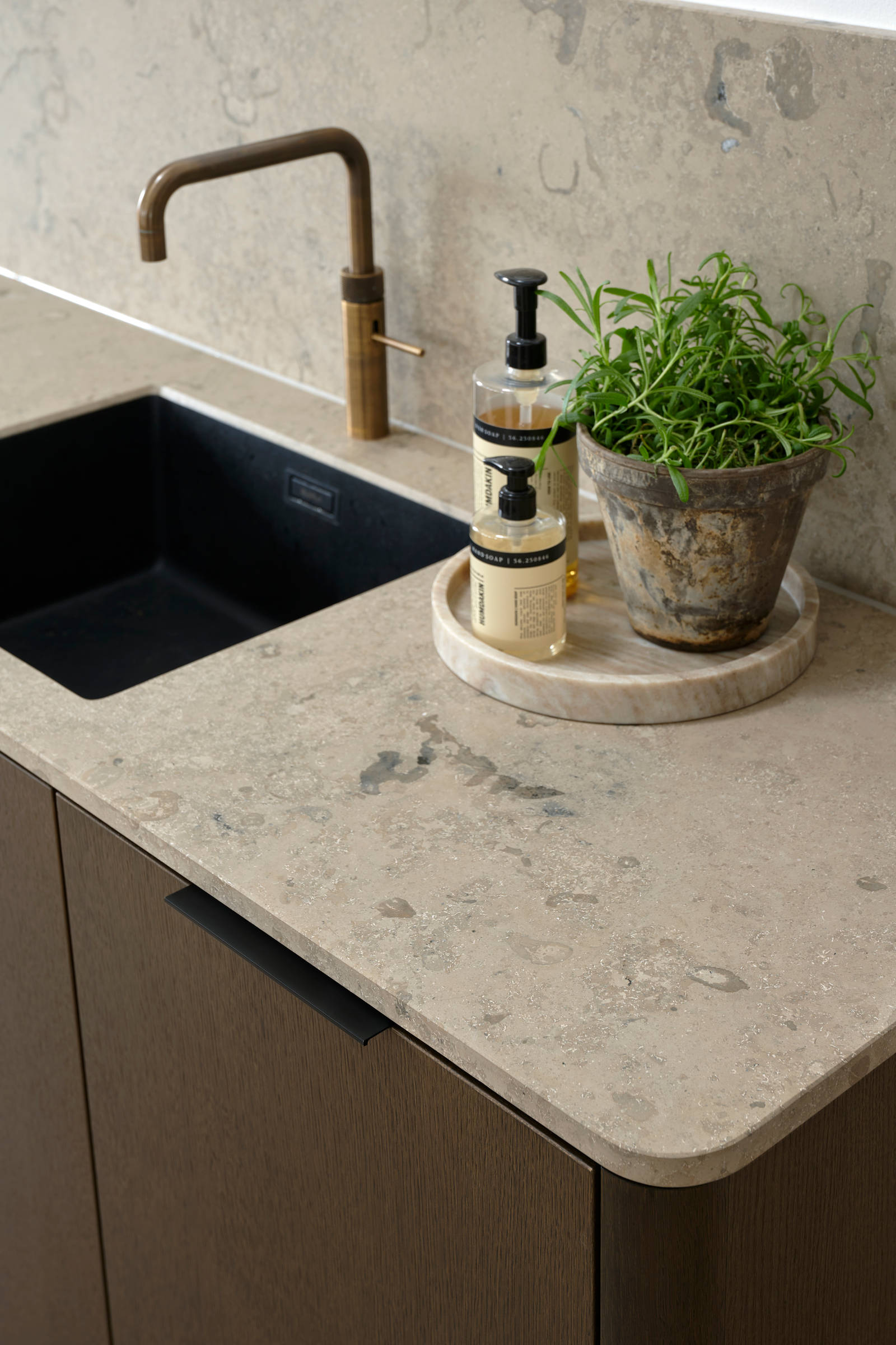 Signatur Ekbacken-kök med köksö, mörka träfronter, bänkskiva och stänkskydd i marmor, svart handfat och mässingsblandare