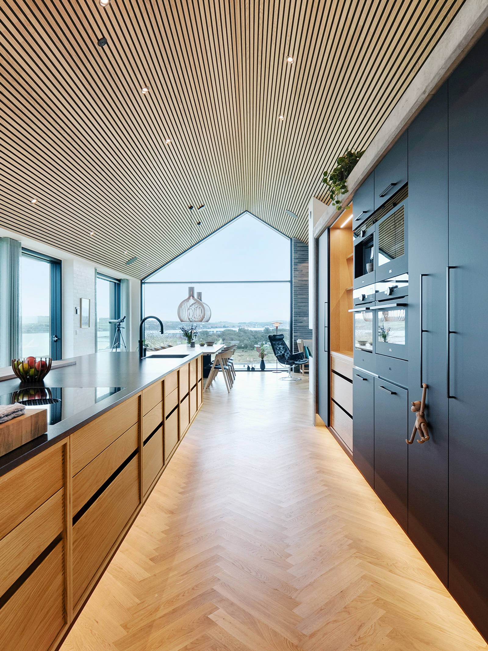 Kitchen island in oak and tall cabinets in matt black laminate