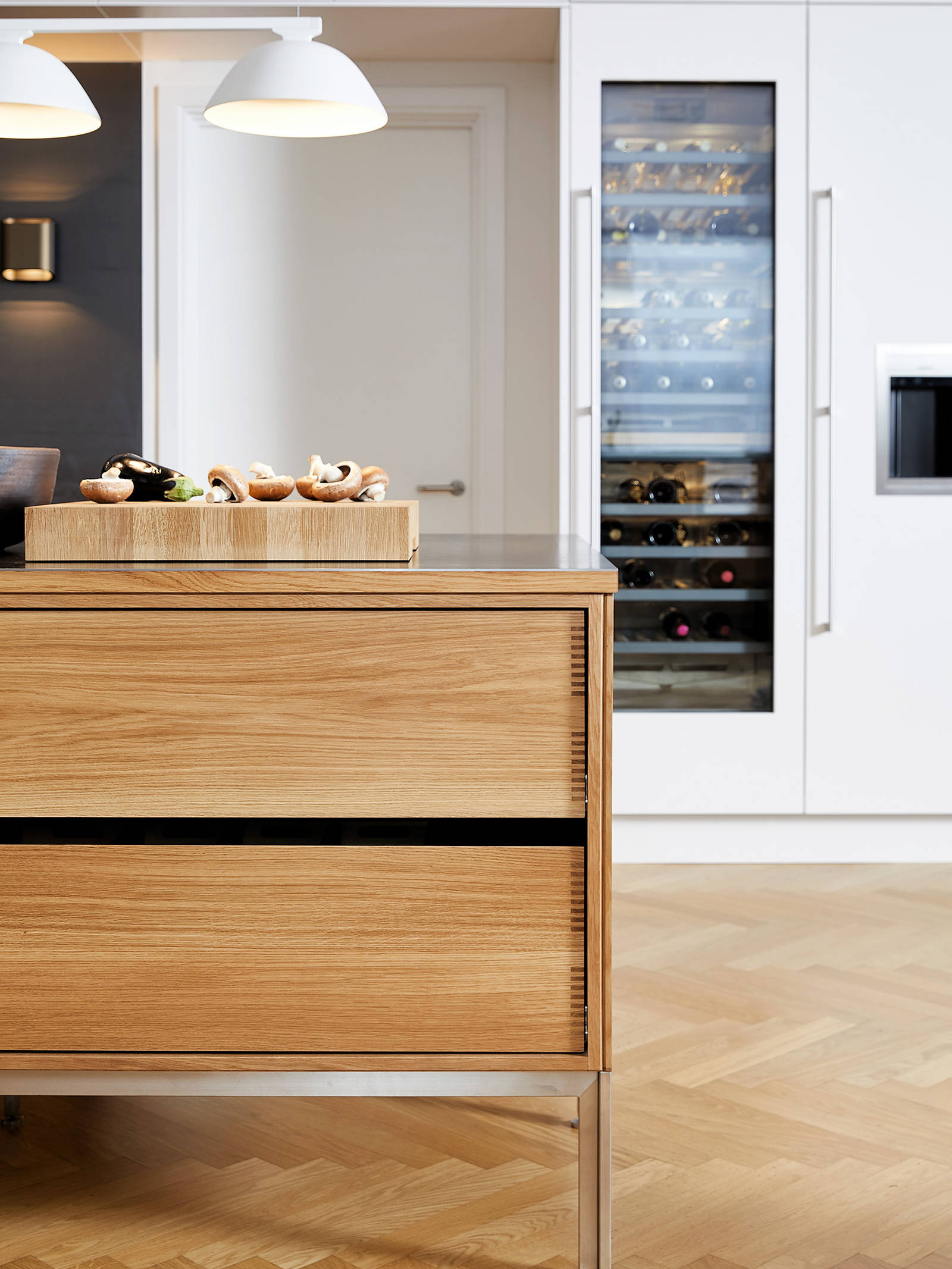 Kjøkkenøy i eik og hvit høyskapsvegg med vinskap