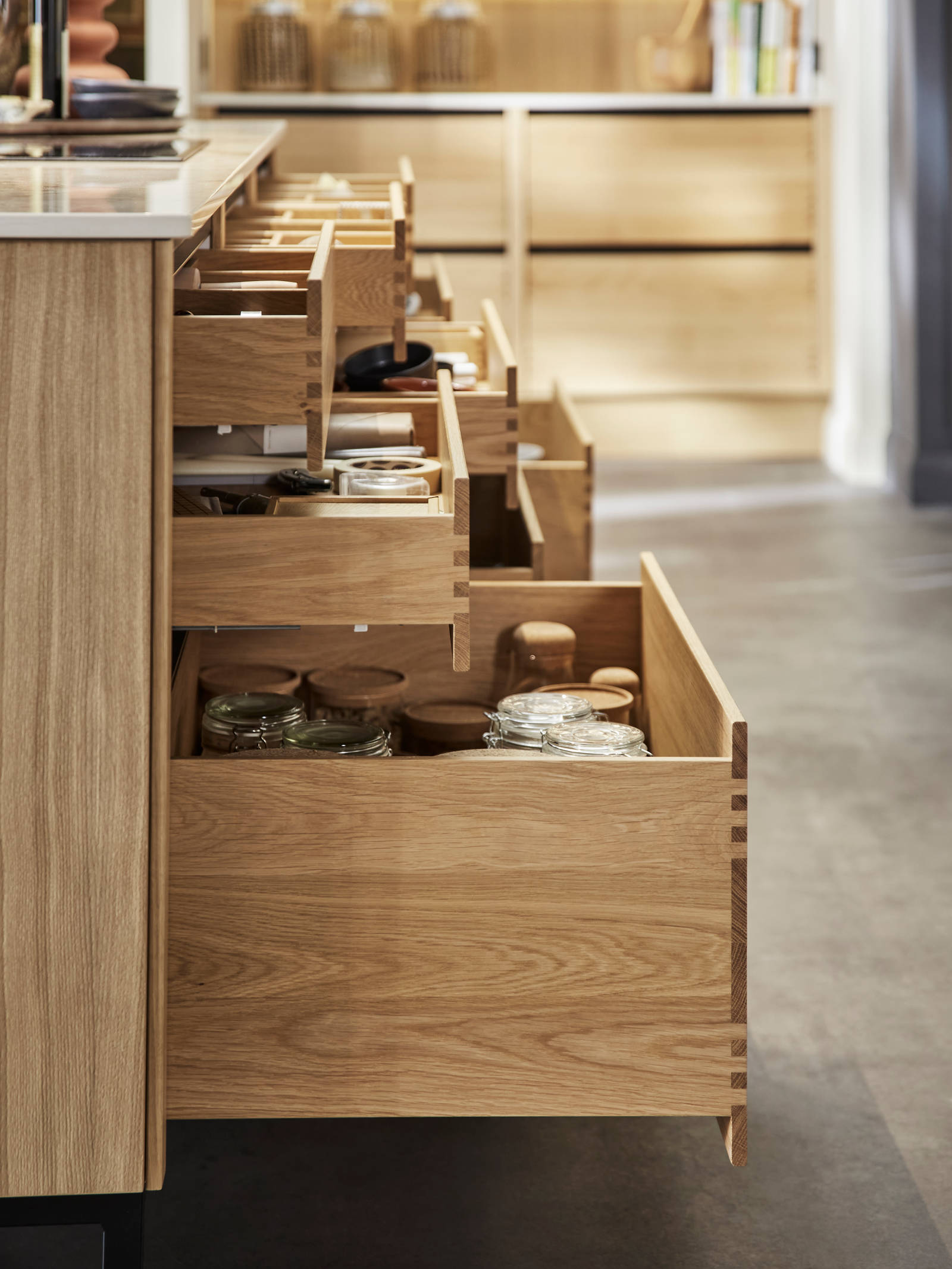 Side view of opened oak drawers in Nordic Craft kitchen island, drawers containing beautiful cookery ware.