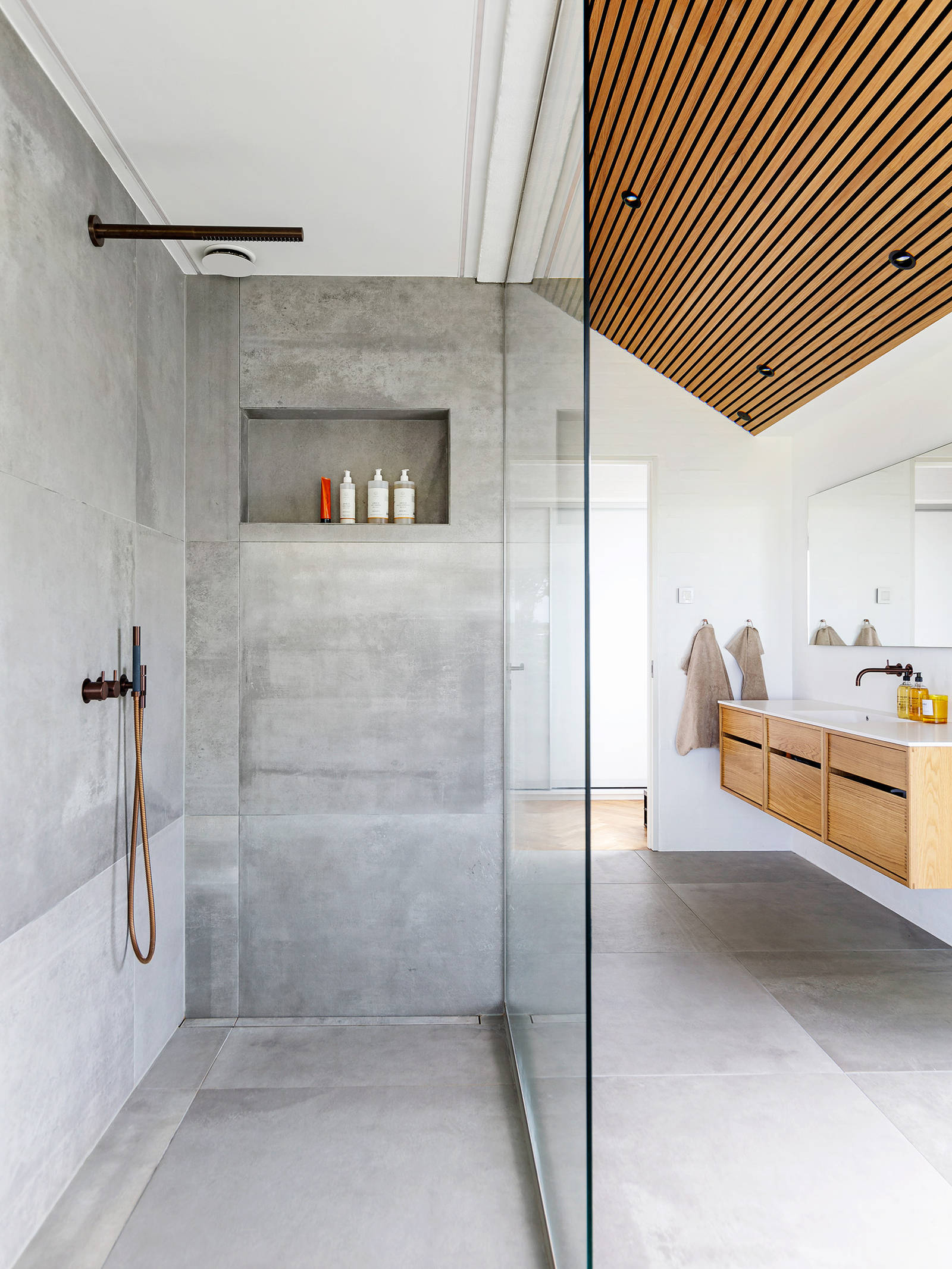The grey tiles in the bathroom are warmly contrasted by the Copenhagen oak cabinets
