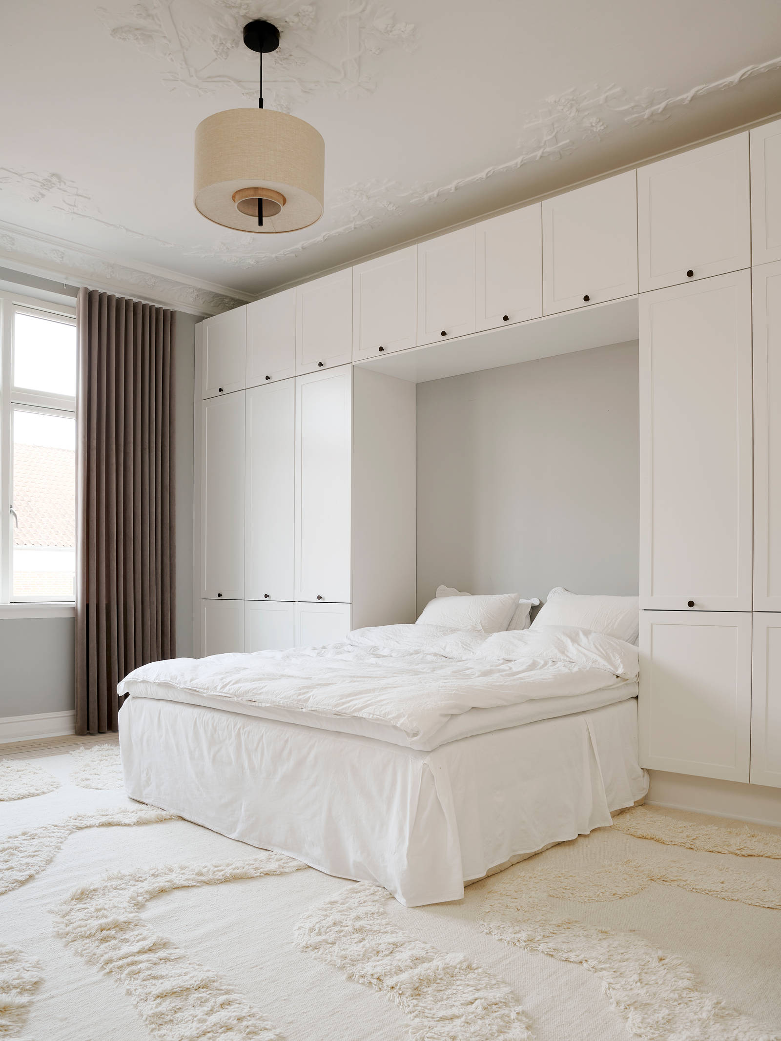 Hvid tidløs garderobe Square Sand fra INVITA omkring en seng med en kommode over, sorte greb på karmdøren