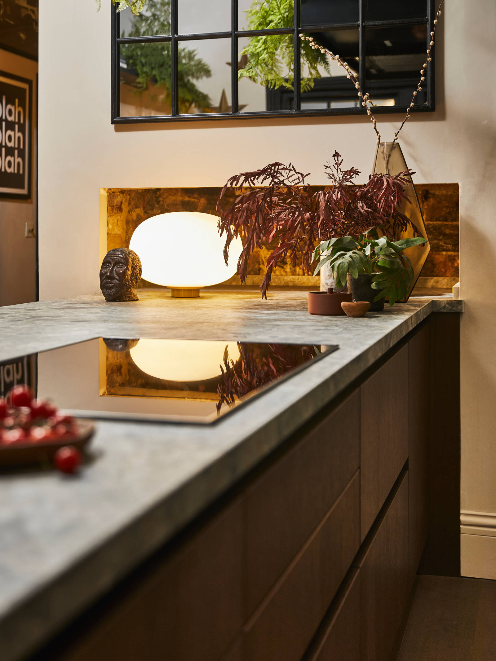 View of Nordic Nature kitchen island with Dekton in Ceppo, hob, potted plants and earth tone decorations