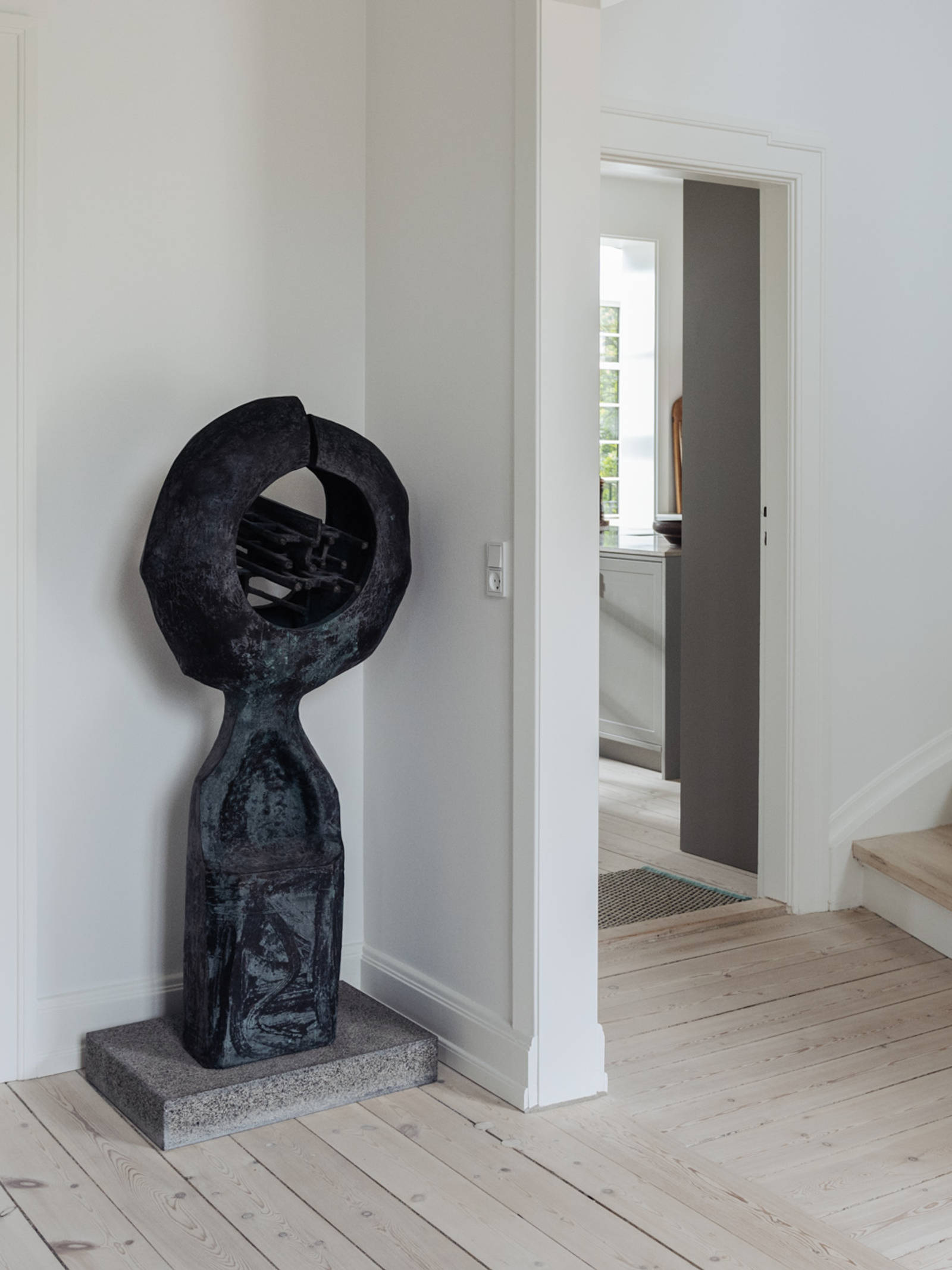 A view from the patrician villa’s hallway, featuring art, toward the grey uno form kitchen