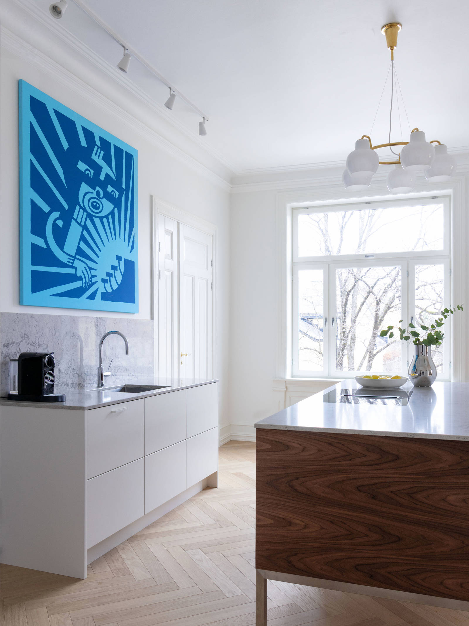 Kontrasterne skaber en harmonisk helhed, hvor køkkenets moderne design indgår i en naturlig dialog med boligens historiske arkitektur.