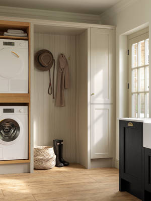 Utility room with Traditional Shaker-style tactile woodgrain Ludlow French Clay cabinets, washing machine and tumble dryer, Ludlow Sumi Black kitchen with brass accessories, Amtico oak stripwood vinyl flooring.