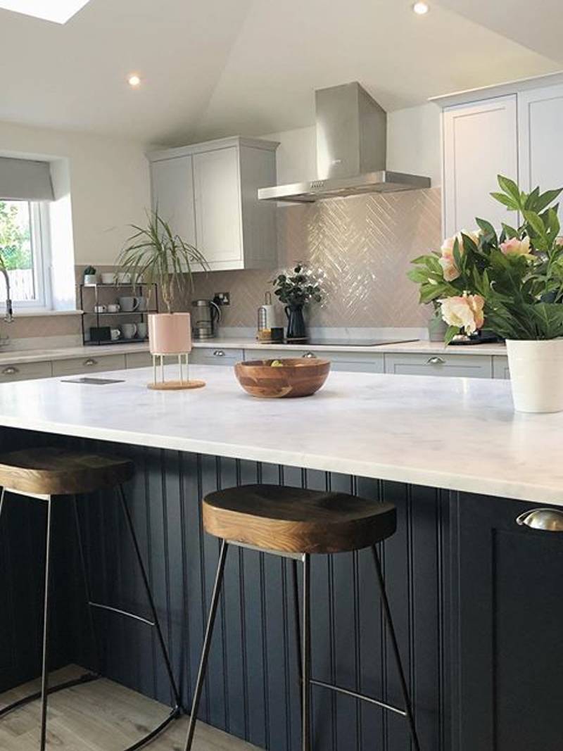 View of the dark blue Midnight kitchen island's bar stool seating area with Carrara White worktop and the matching Dunham cabinetry in Dove Grey.