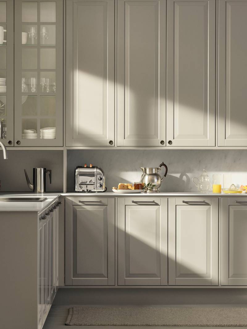 Beige landkøkken Nordic Sand fra INVITA med fyldningslåger, sort håndtag, vitrineskab med sprosselåger og hvid marmor laminatbordplade