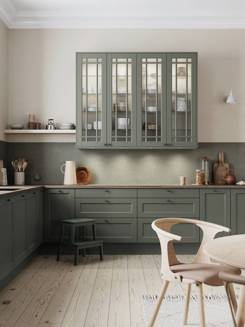Grønn kjøkken med speilfronter, benkeplate i tre og sorte knotter, vitrinedører med sprosser