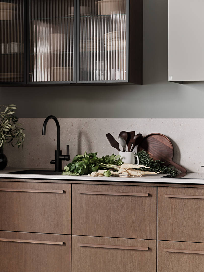 Nærbillede af Køkken Forever Oak fra INVITA, mørk eg køkkenskabe med massiv tre mørk eg håndtag, komposit bordplade, sort armatur og vitrineskab med riflede glas i tynd, sort aluminiumsramme