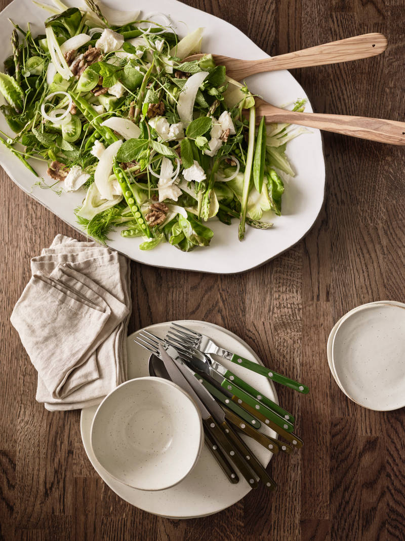 Bordplade i massivt træ ovenfra med porcelæn og en salat lagt ud