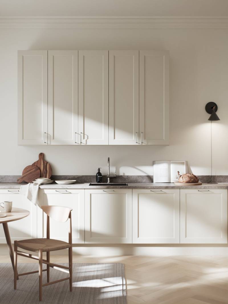 Tidløs beige kjøkken som har en 5-delt speilfront med profilert innerkant og slett speil, stål håndtak og kran, grå marmor benkeplate med spisebord og stoler i lys tre.