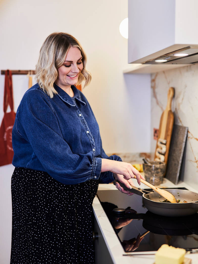 Jen stirring in a pan on the stove and smiling