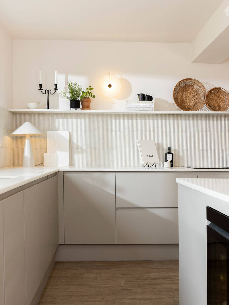 View of Yasmin Wyatt's open, light and airy neutral shade handleless Luna kitchen from Magnet, a white Corian worktop in Onyx, wine fridge integrated into kitchen island.