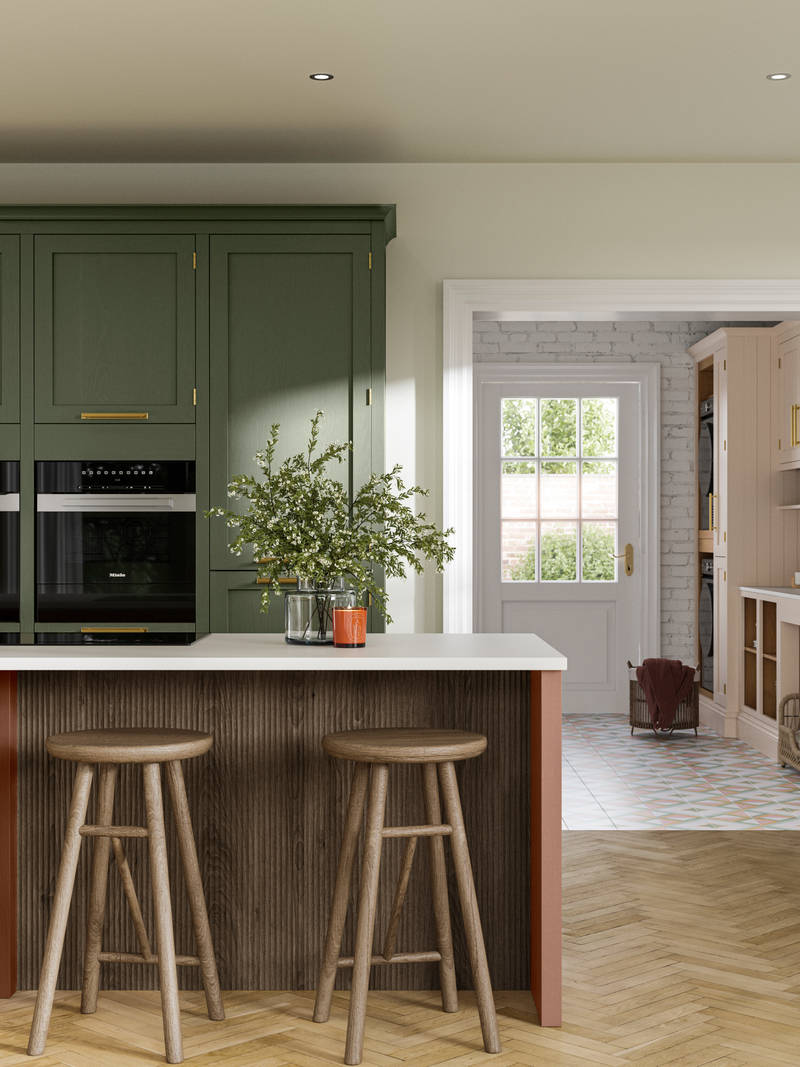Tall Wardley kitchen cabinets  with built-in ovens, a kitchen island in shade Clay with wooden panelling by seating area and matching wooden bar stools.