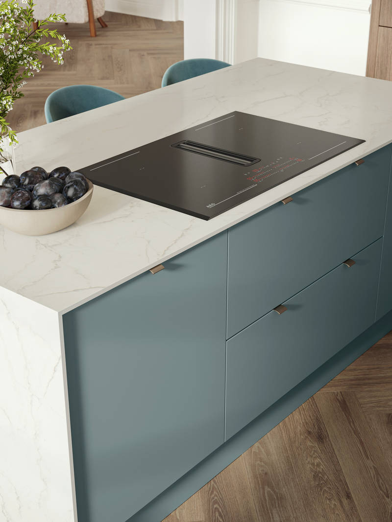Overhead view of kitchen island with marbled dekton worktop, integrated hob and Soho Duck Blue cabinetry from Magnet.