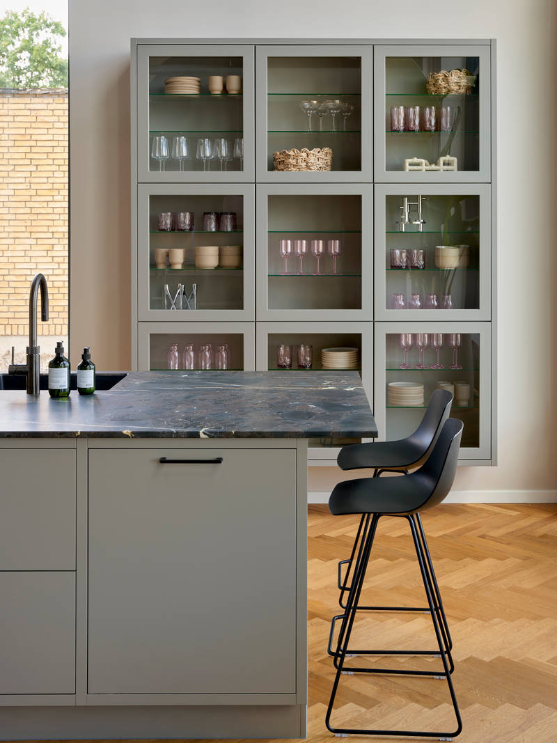 Grå køkkenø med barstole og vitrineskabe i INVITAs butik