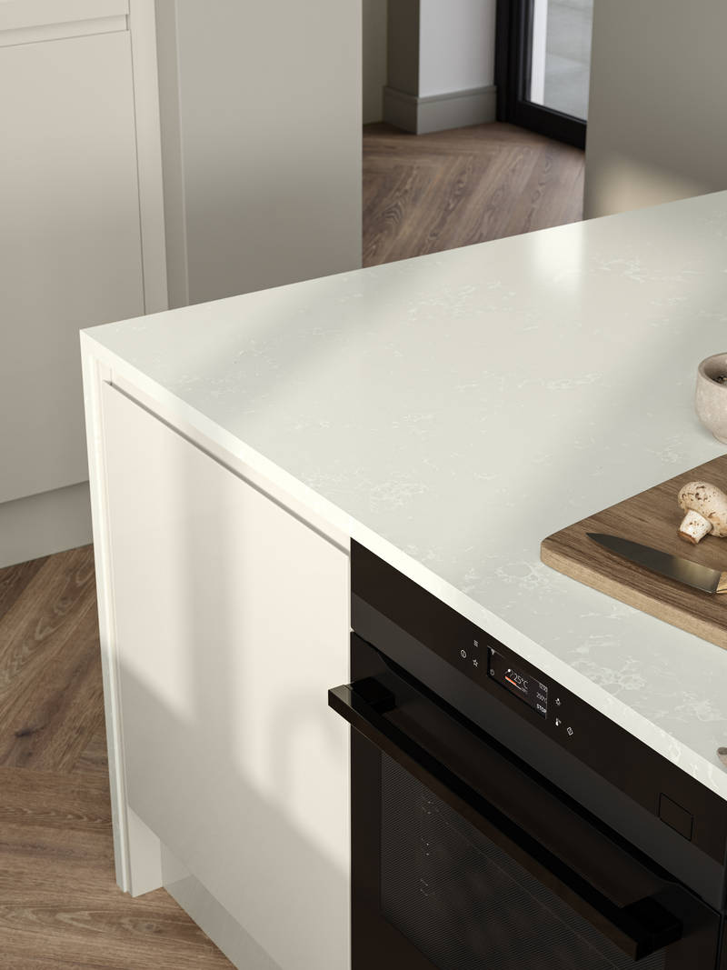 View of wood cutting board and knife with mushrooms on Minerva chalk venato worktop covered contemporary Luna Gloss Limestone kitchen island with integrated oven, Amtico smouldering oak parquet flooring.
