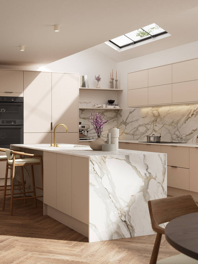Fluted front kitchen Reed from Magnet in light warm neutral shade Shell, with a marbled splashback, worktop and decorative side on kitchen island with barstools and black handles, herringbone wood flooring.