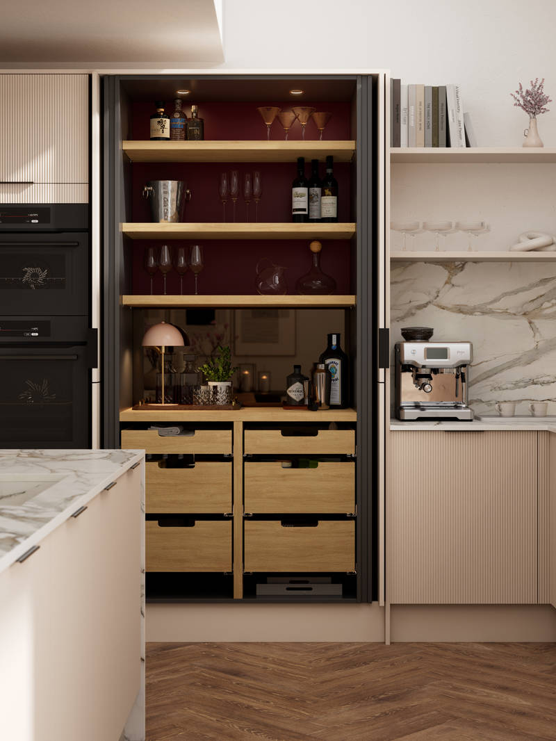 Fluted front kitchen Reed from Magnet in light warm neutral shade Shell, with a marbled splashback and worktop, opened pocket larder cabinet, black handles