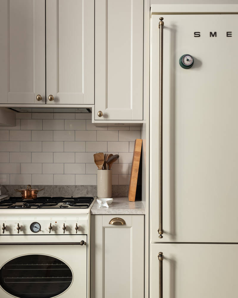 Sandra Beijers kök från Marbodal, lantliga luckan Fagerö i beige kulören Sand, med bronsfärgade handtag, bänkskiva i ljus kalksten beige kylskåp från Smeg.