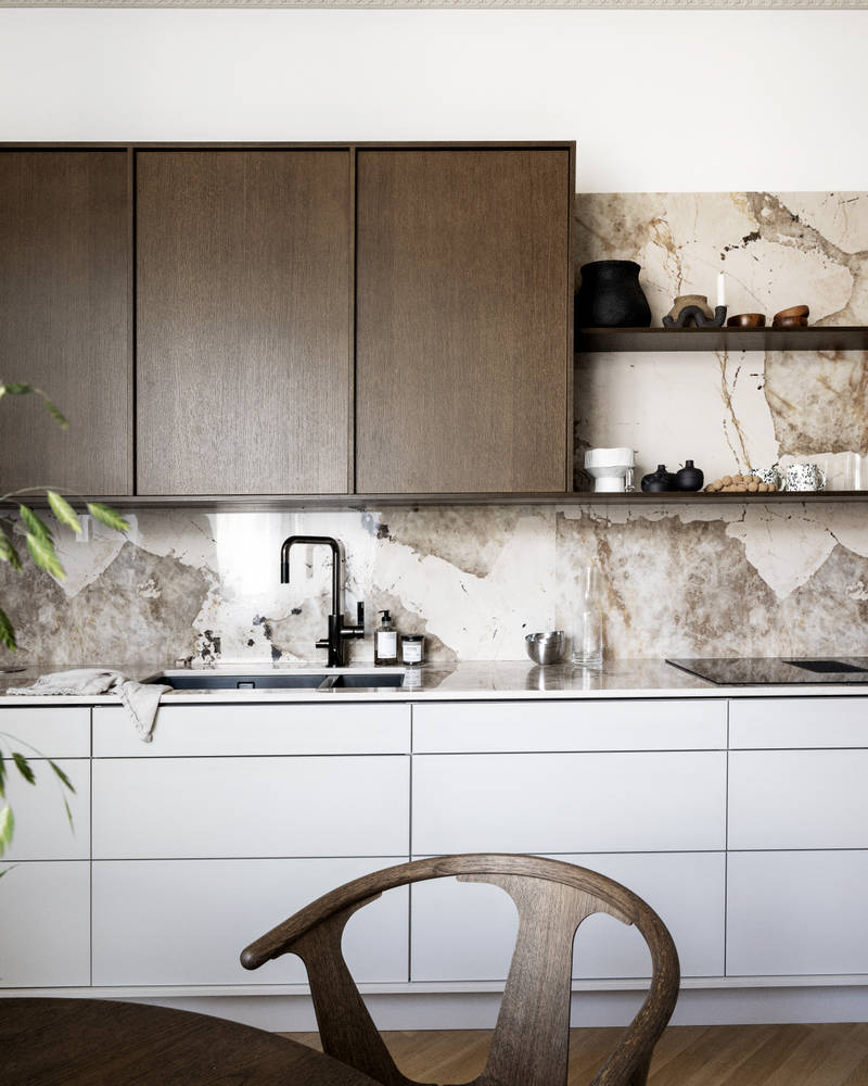 Kjøkken med kombinasjon av kjøkkenbenk i beige Line Korn med overskap i Favn finert eikedør i brunbeis fra Sigdal, benkeplate og sprutbak som matcher, og åpne vegghyller i brunbeiset eikefiner.